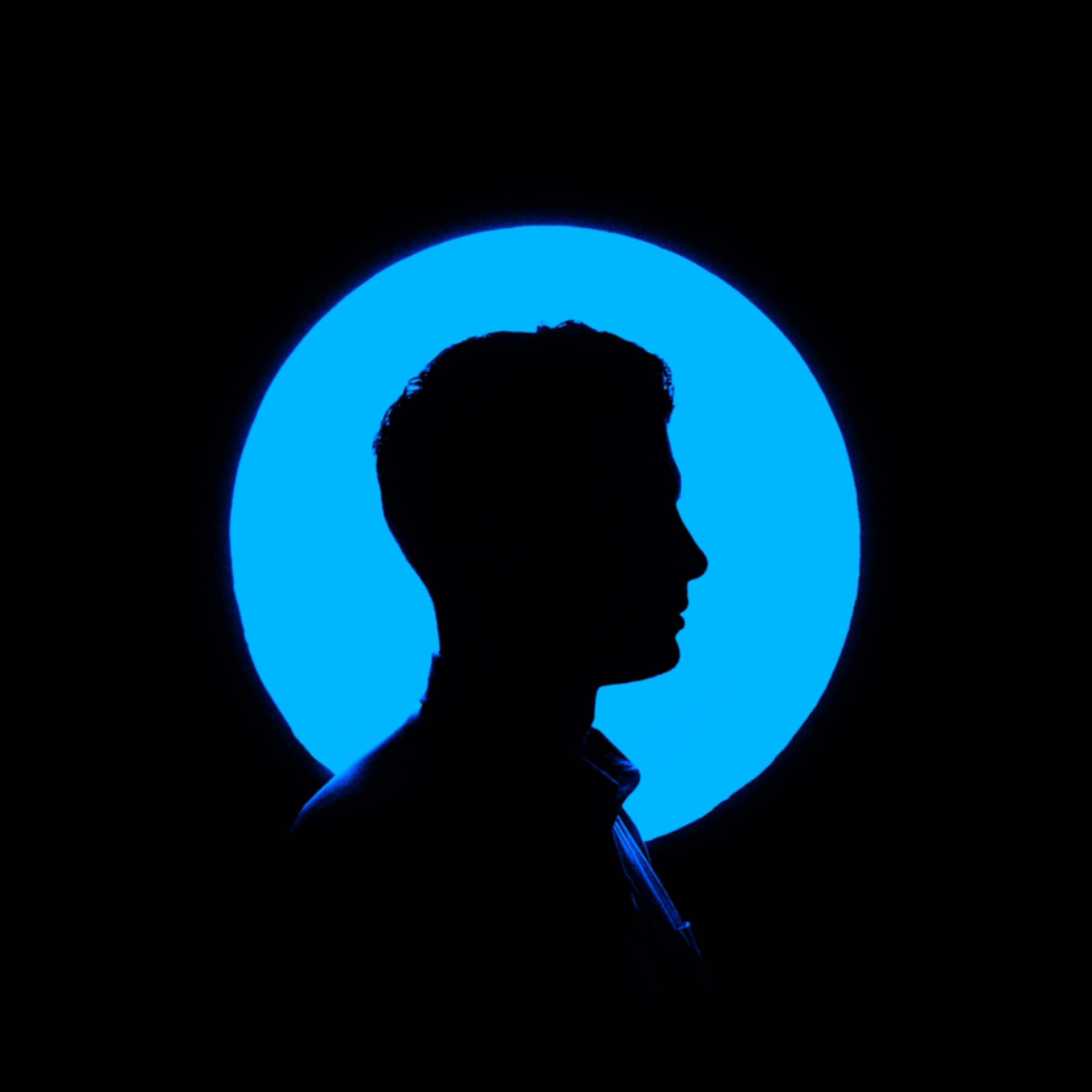 Man's profile silhouette against a glowing blue circle on a black background.