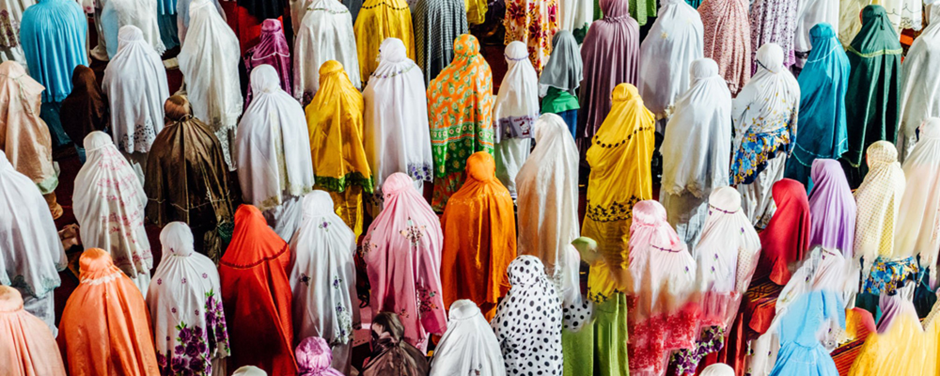A large group of people wearing diverse colorful prayer garments.