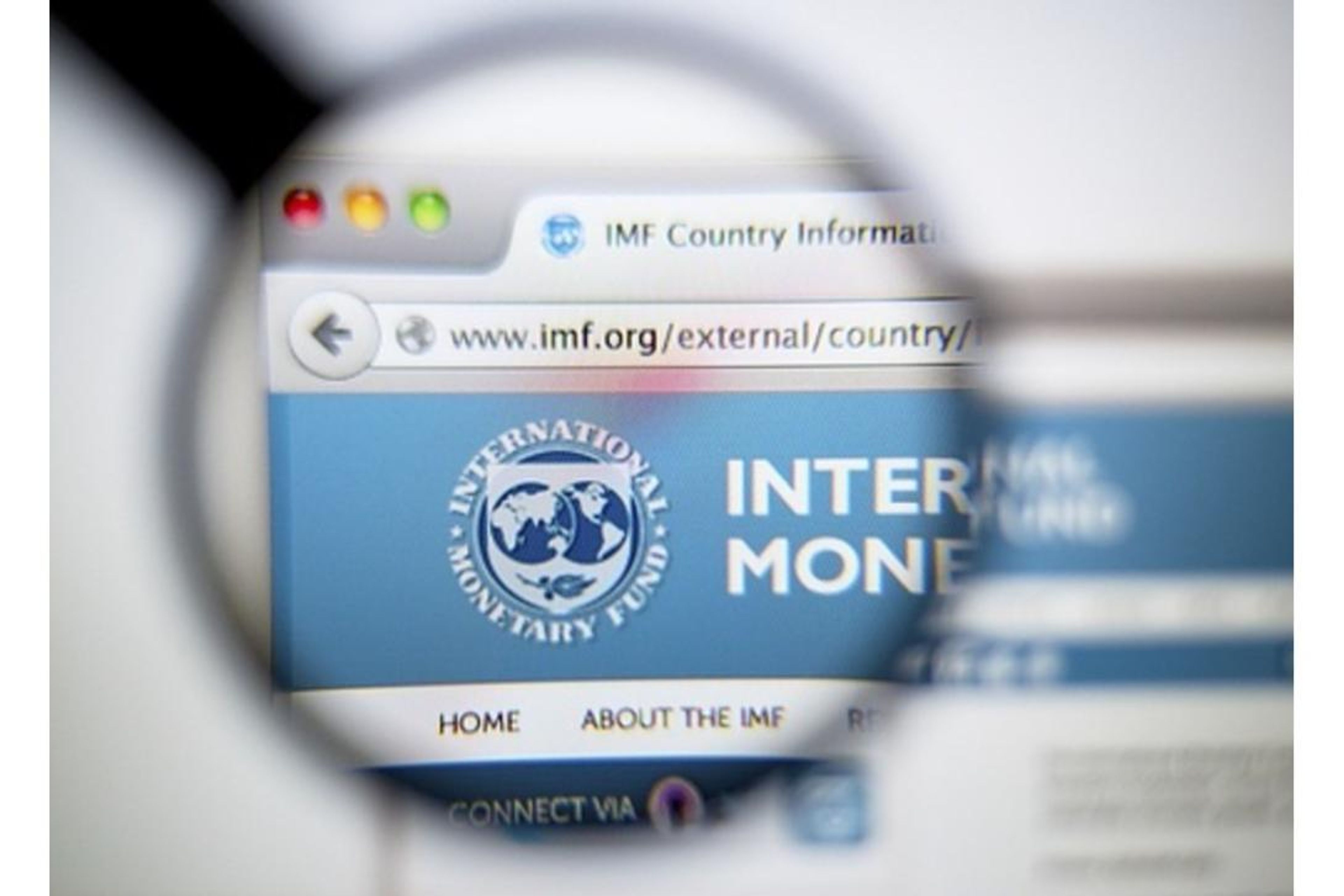 Magnifying glass over a web browser displaying the IMF website.