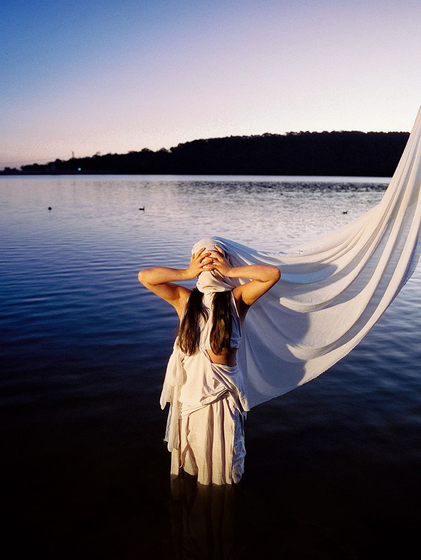 Woman with flowing fabric by water