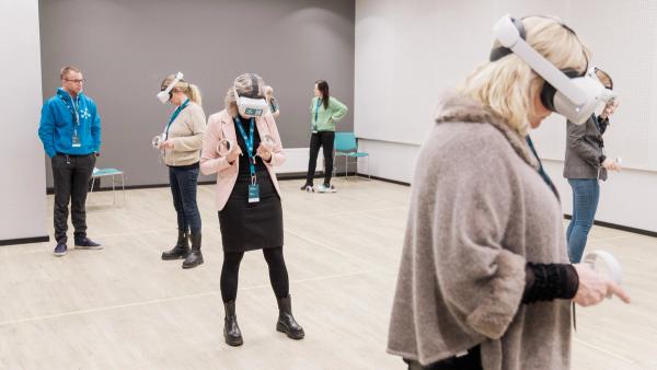 Et rom fullt av mennesker som står med VR-briller på og trener på medisinske ferdigheter i VR.