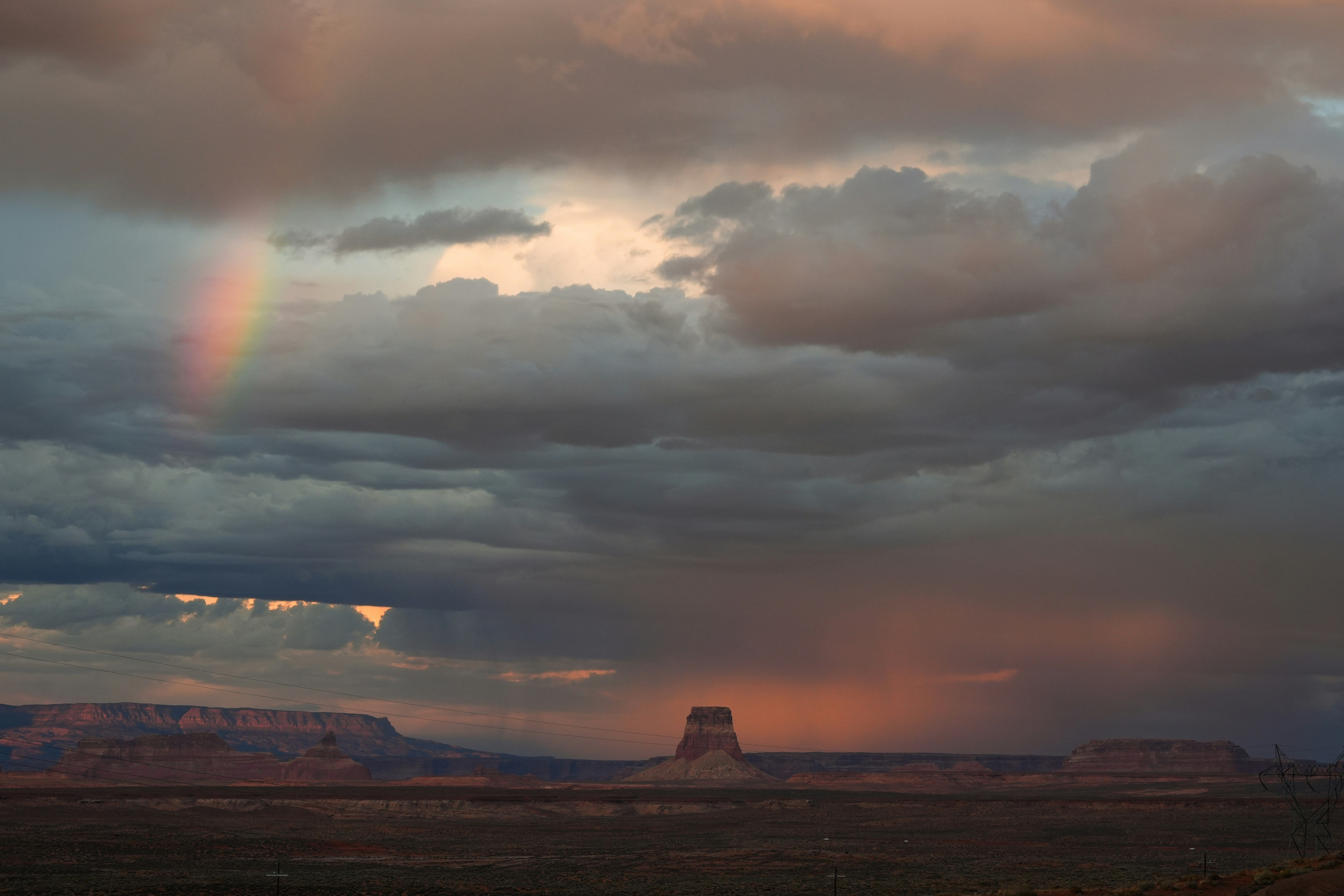Rainbow appears in stormy desert landscape at sunset