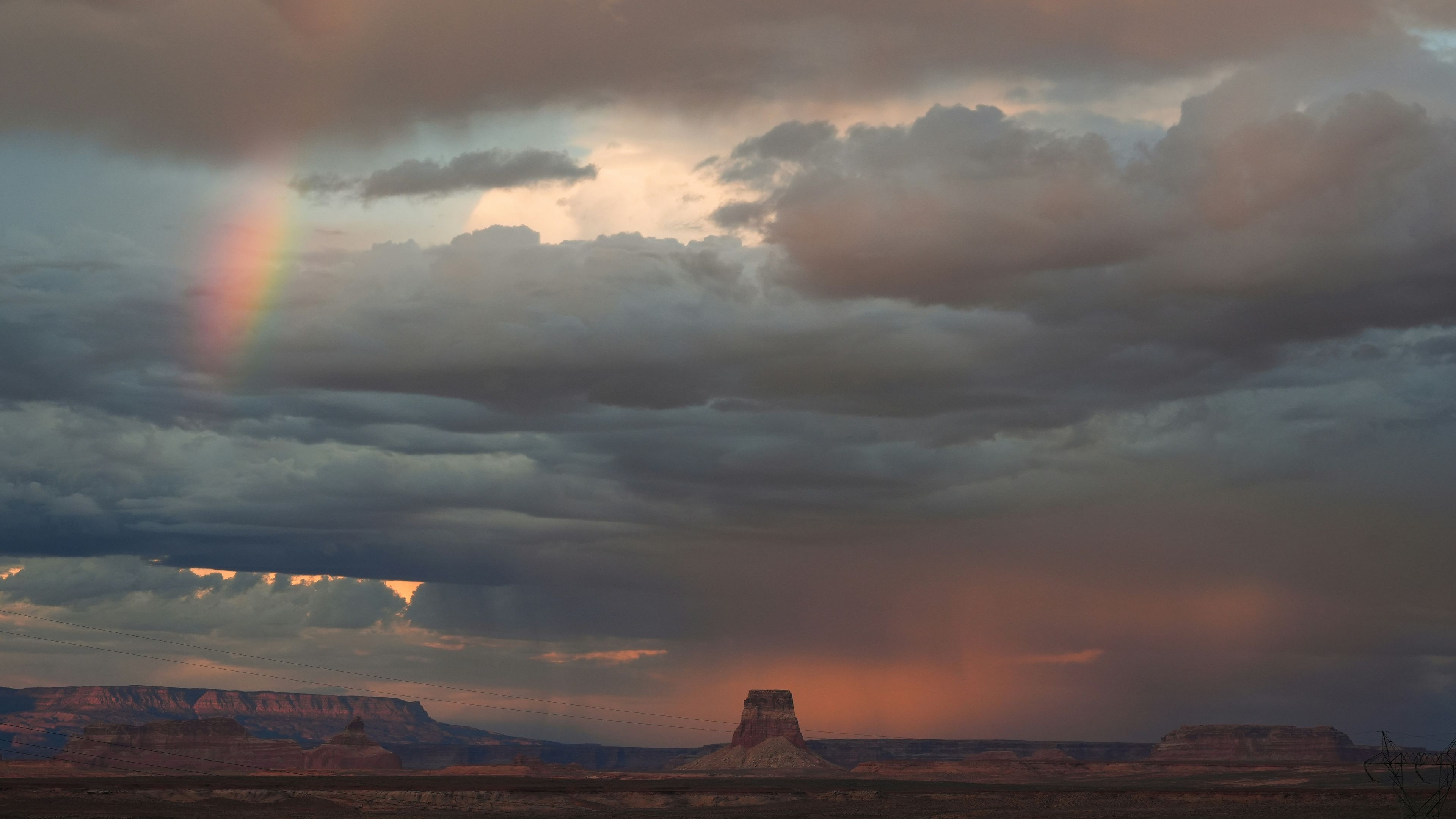 Rainbow appears in stormy desert landscape at sunset