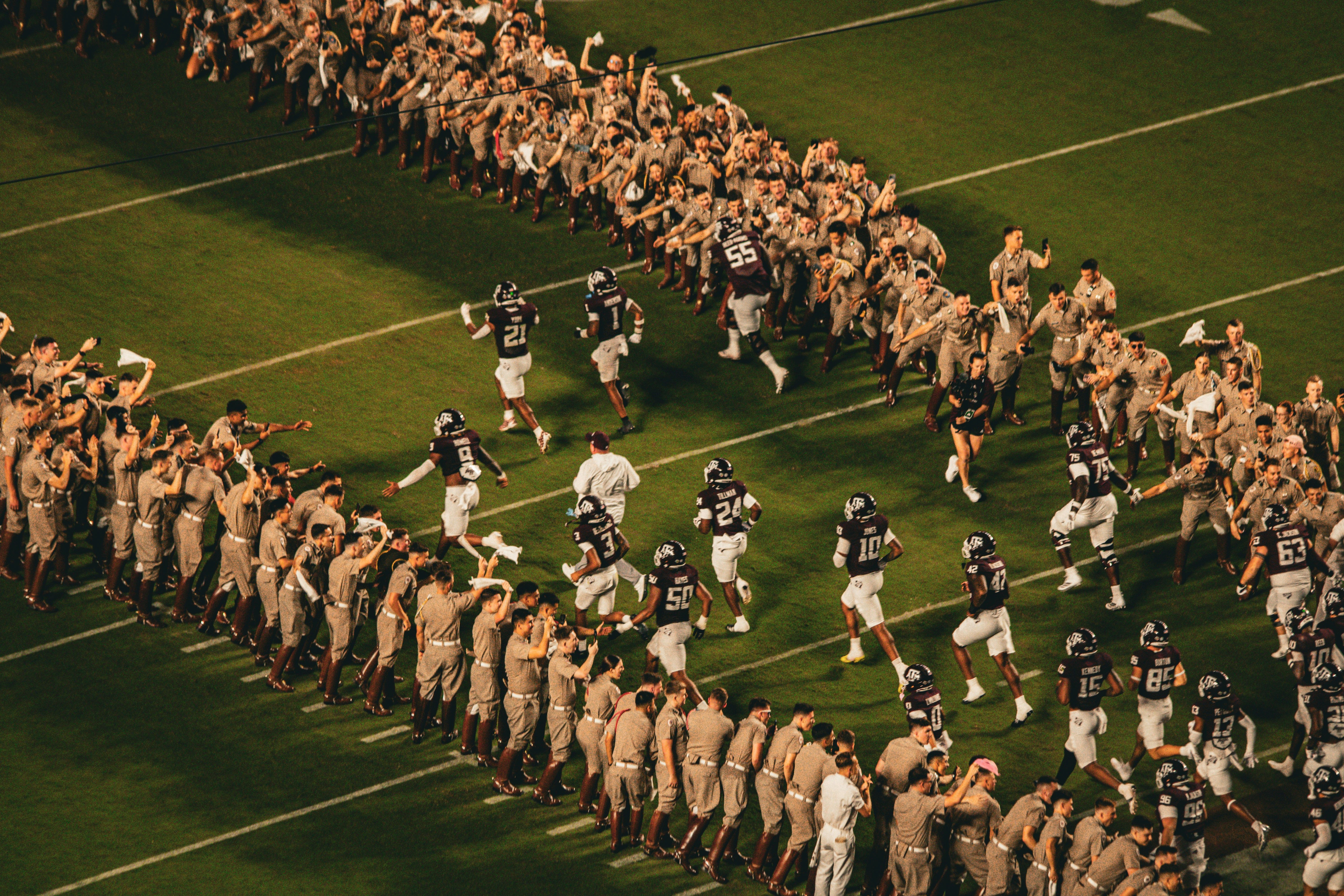 Football players run onto the field between cheering crowds