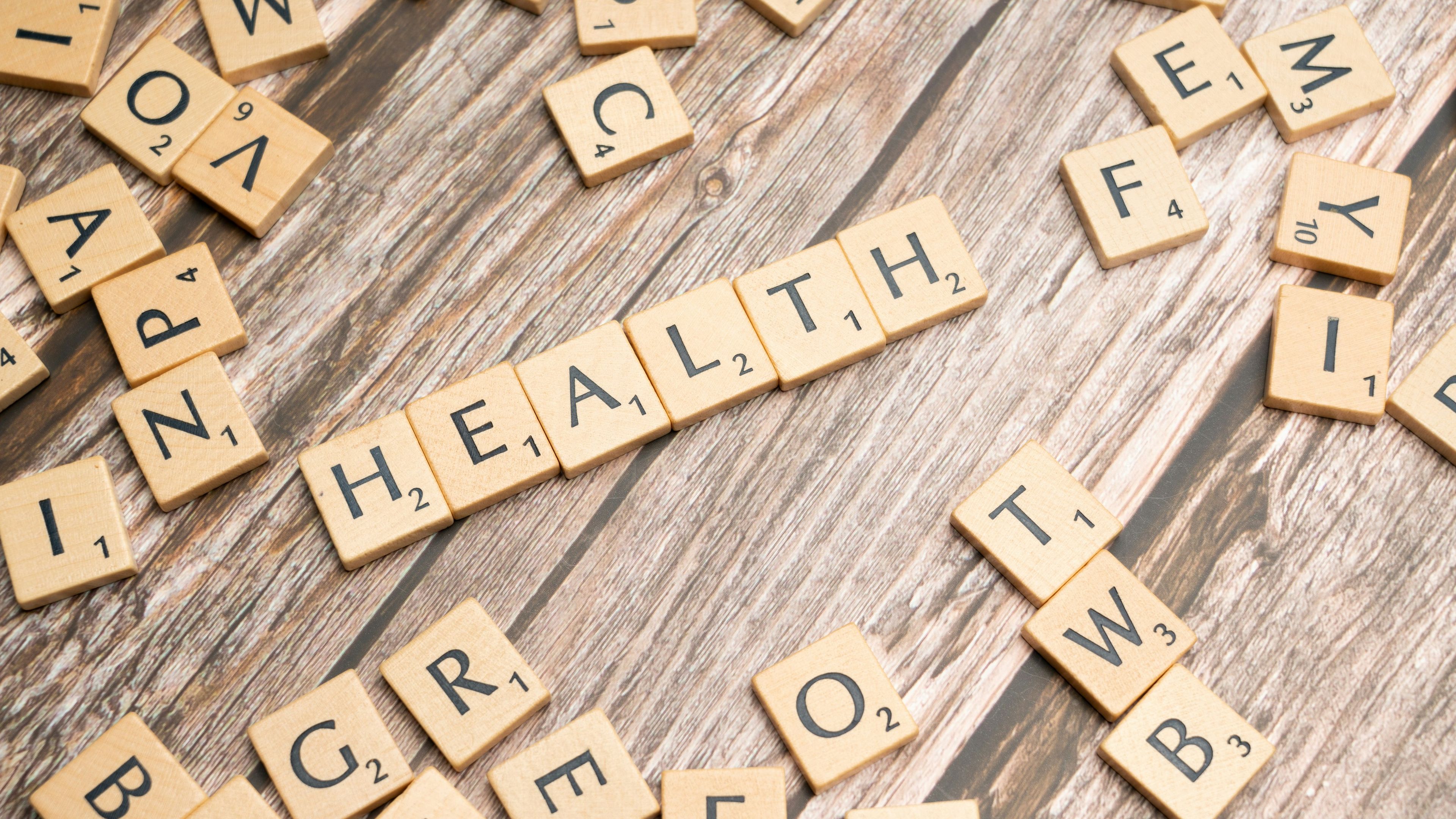 Scrabble tiles spelling the word health on a wooden surface