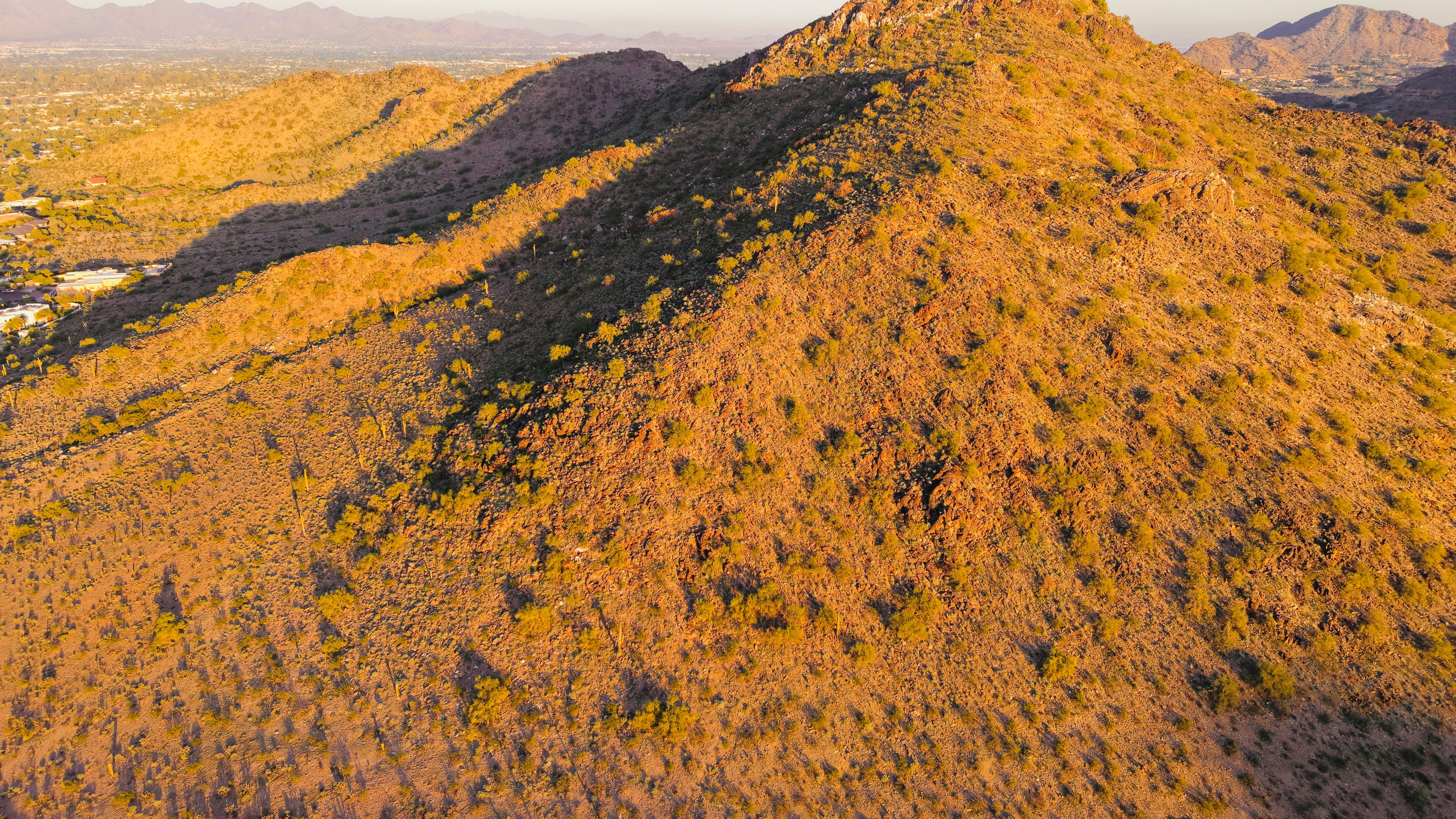 Golden hour illuminates a dry, rocky desert mountain landscape