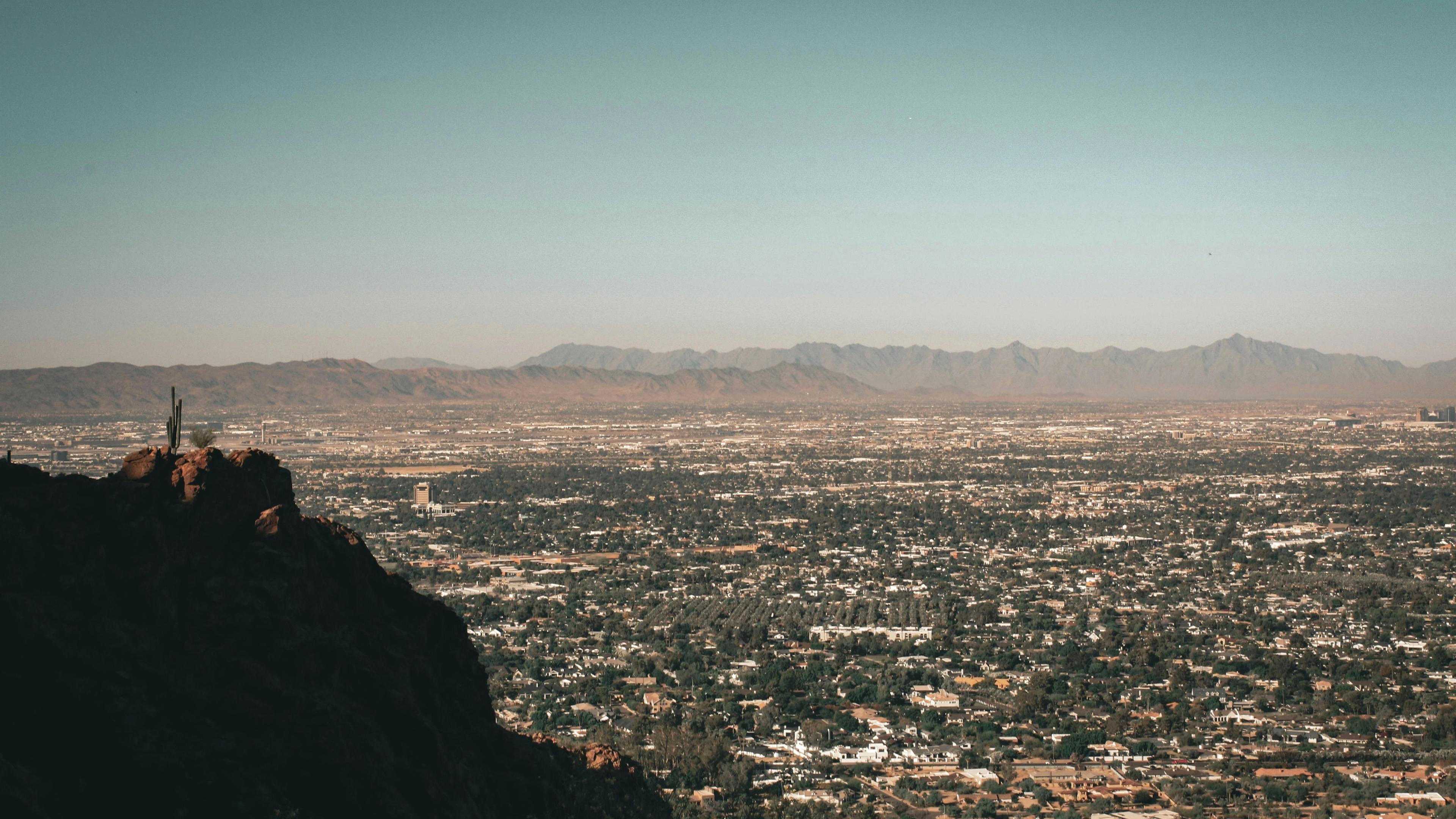 Person sitting on rock looking at city during daytime