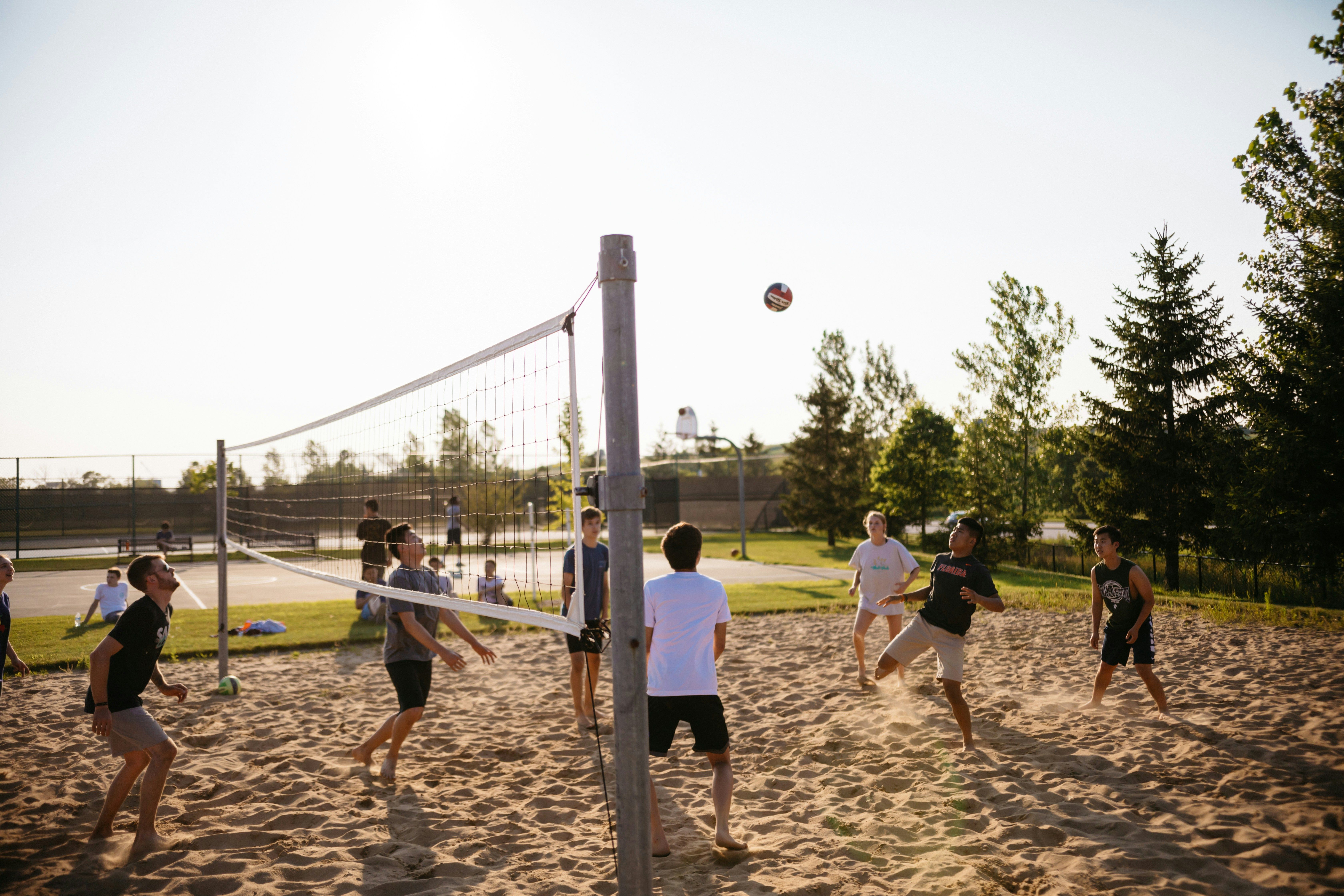 Men playing volleyball near pine trees