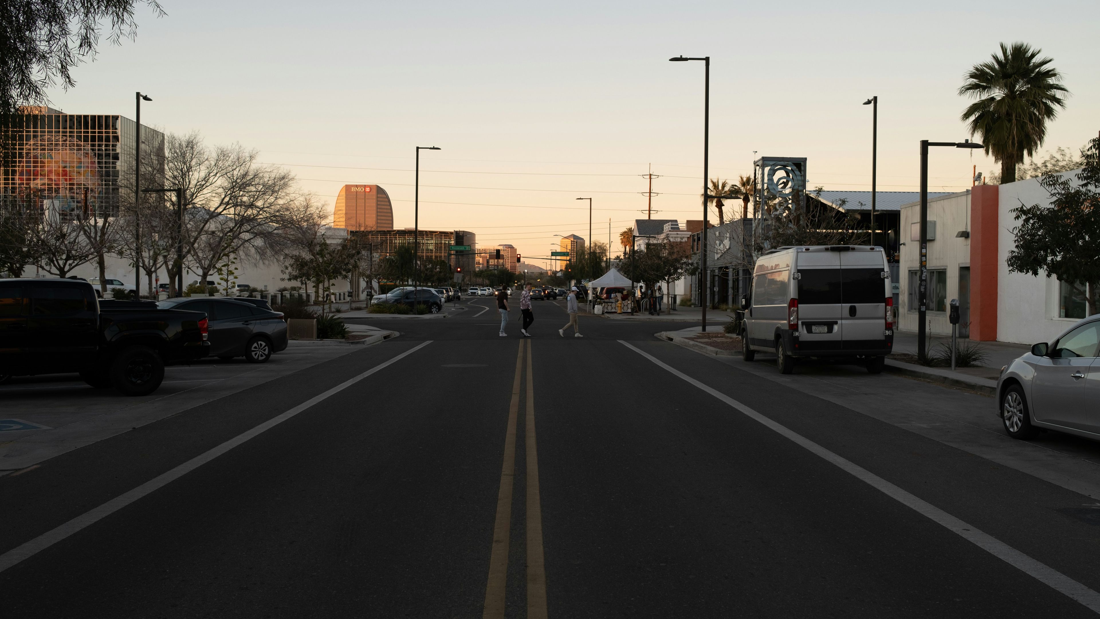 A street lined with parked cars and palm trees