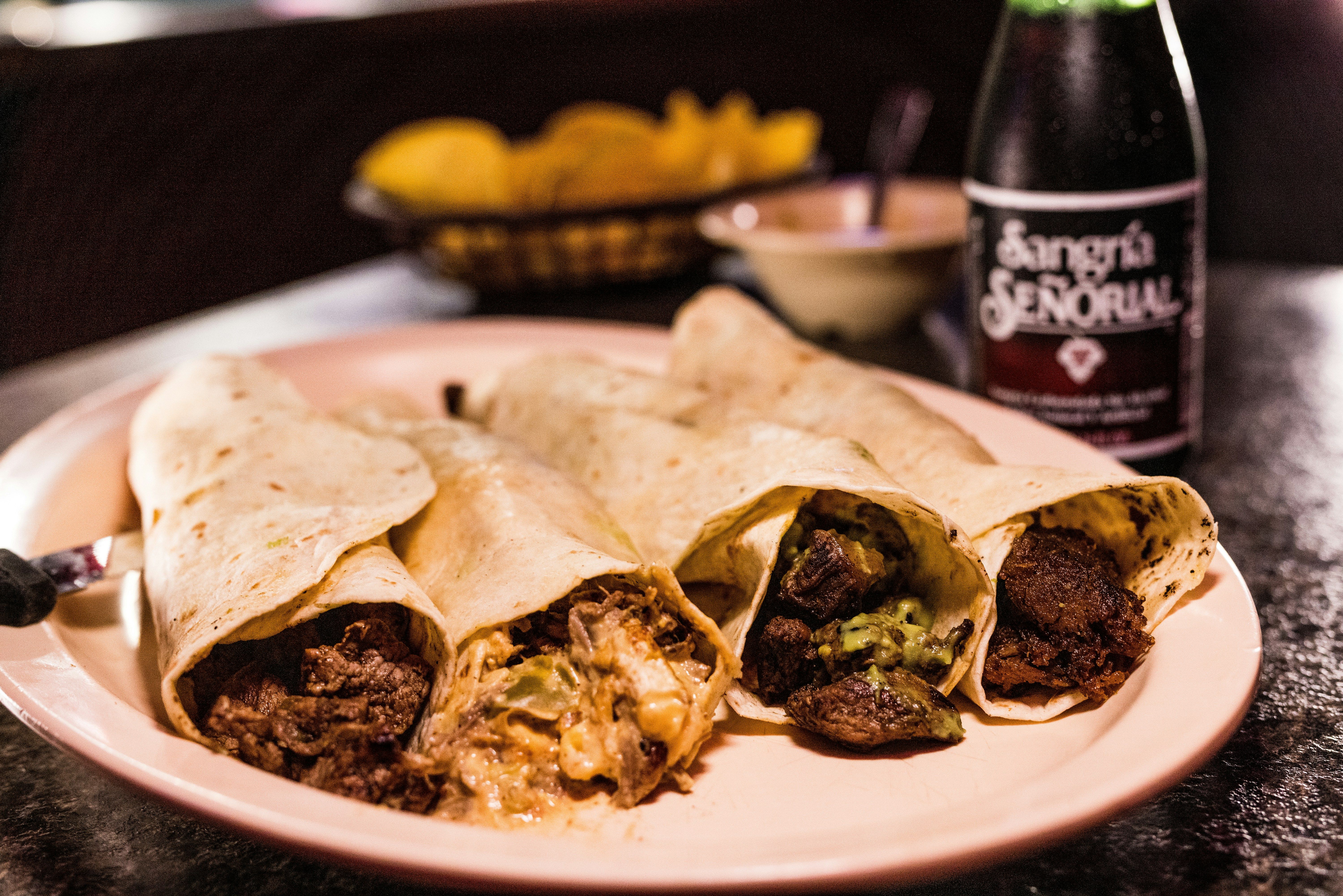 A burrito cut in half on a plate next to a bottle of beer