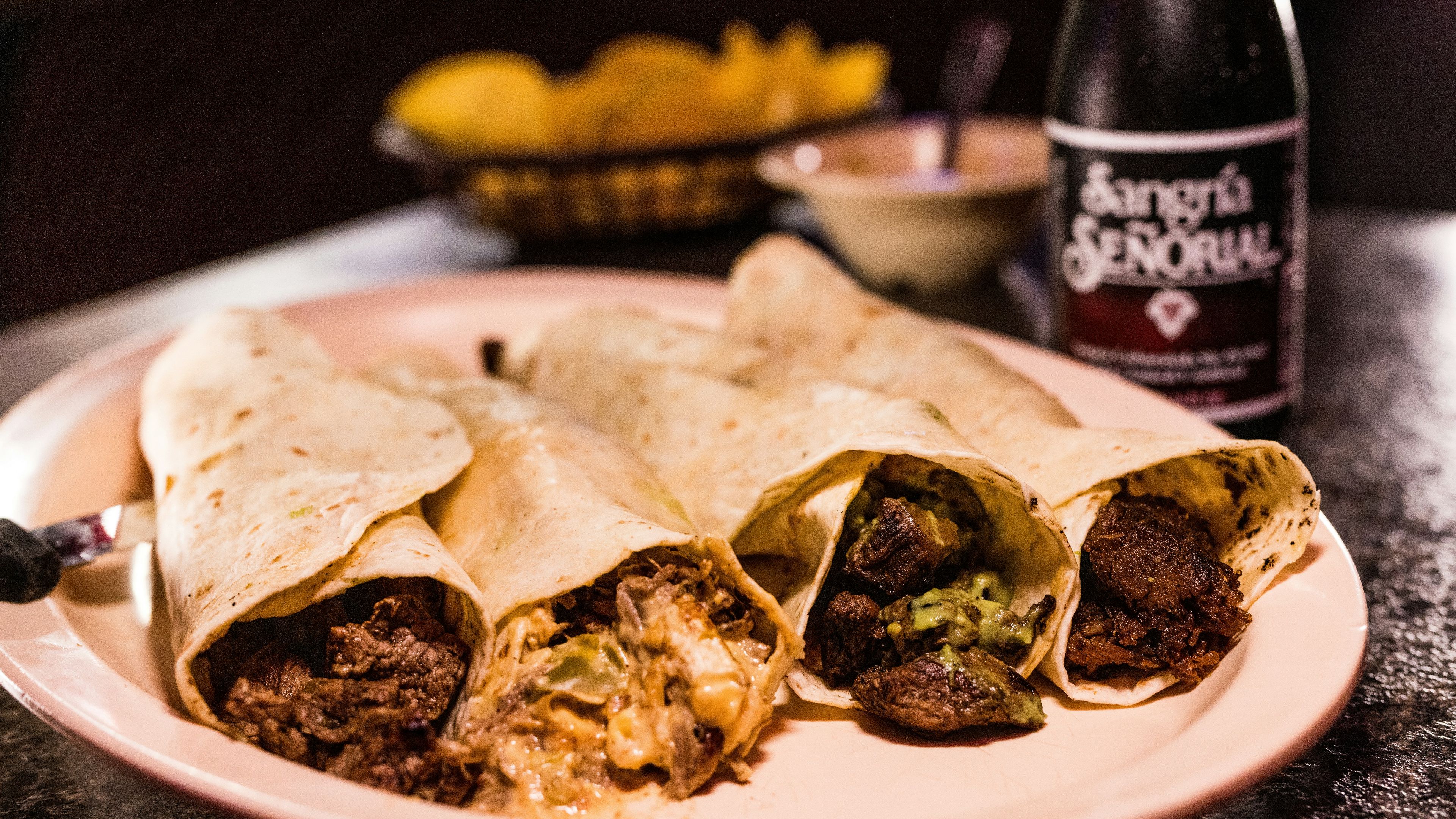 A burrito cut in half on a plate next to a bottle of beer