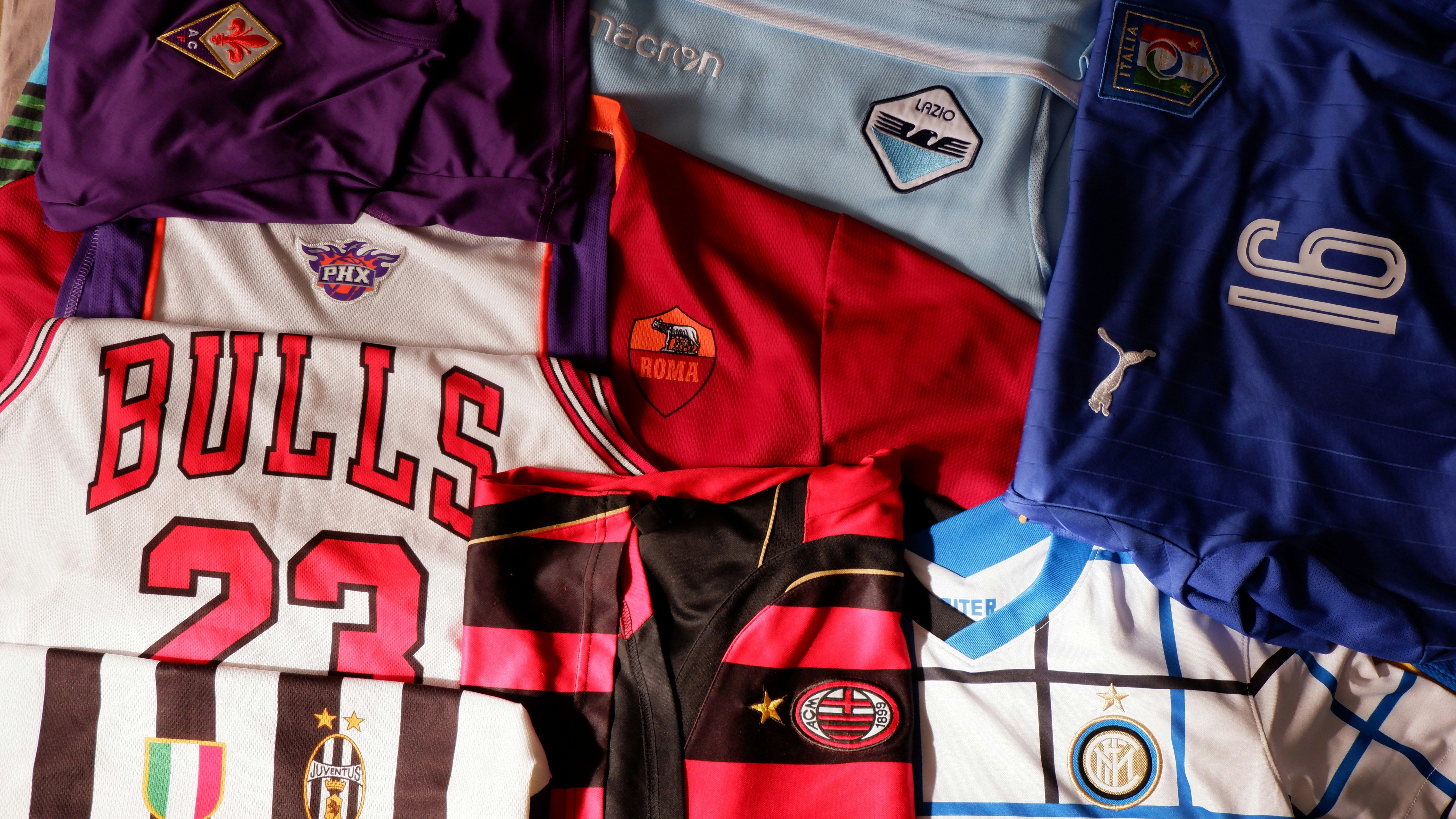 A pile of sports jerseys sitting on top of a bed