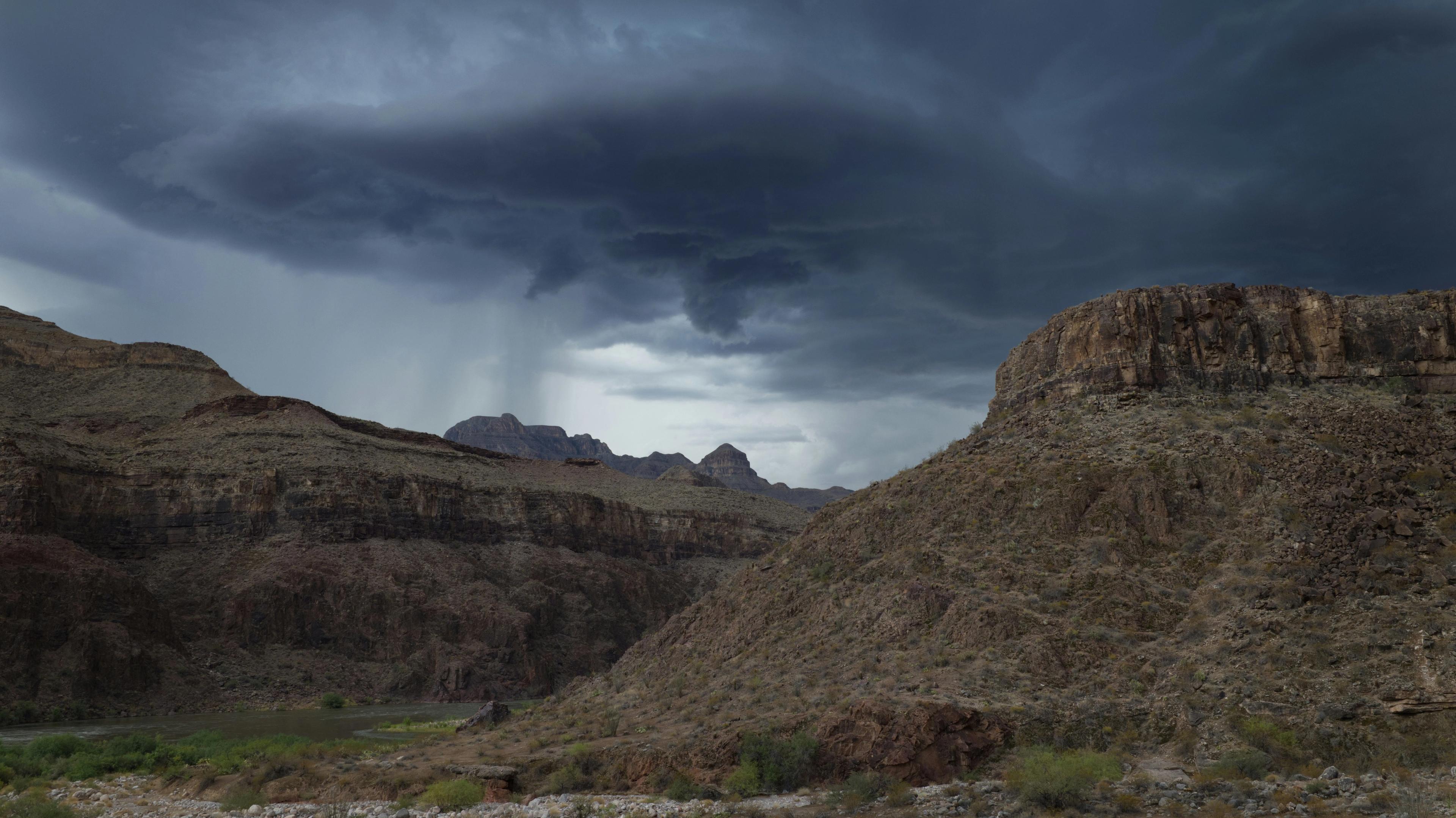 Storm clouds gather over a rugged desert landscape