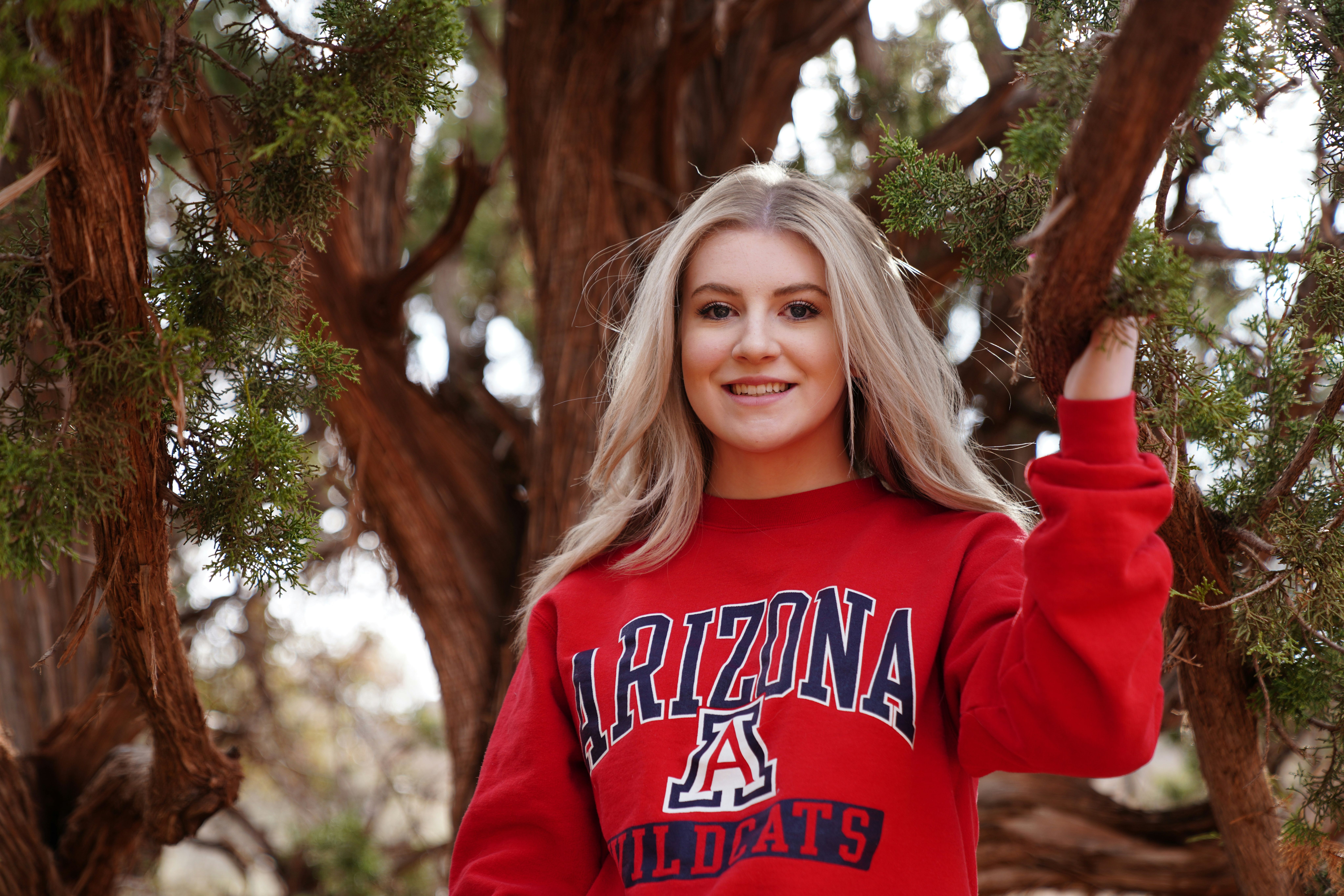 A woman is wearing an arizona wildcats sweater