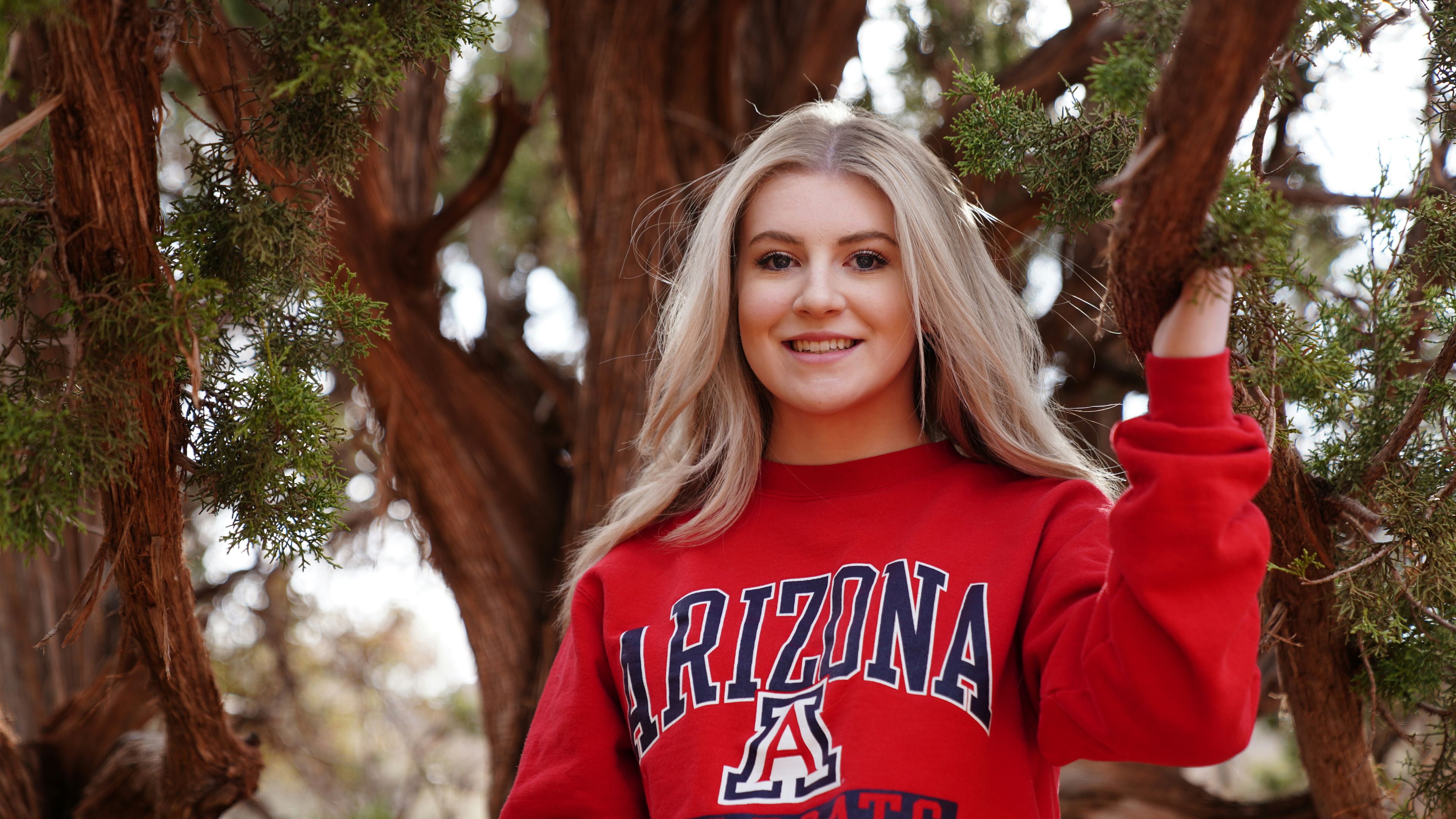 A woman is wearing an arizona wildcats sweater