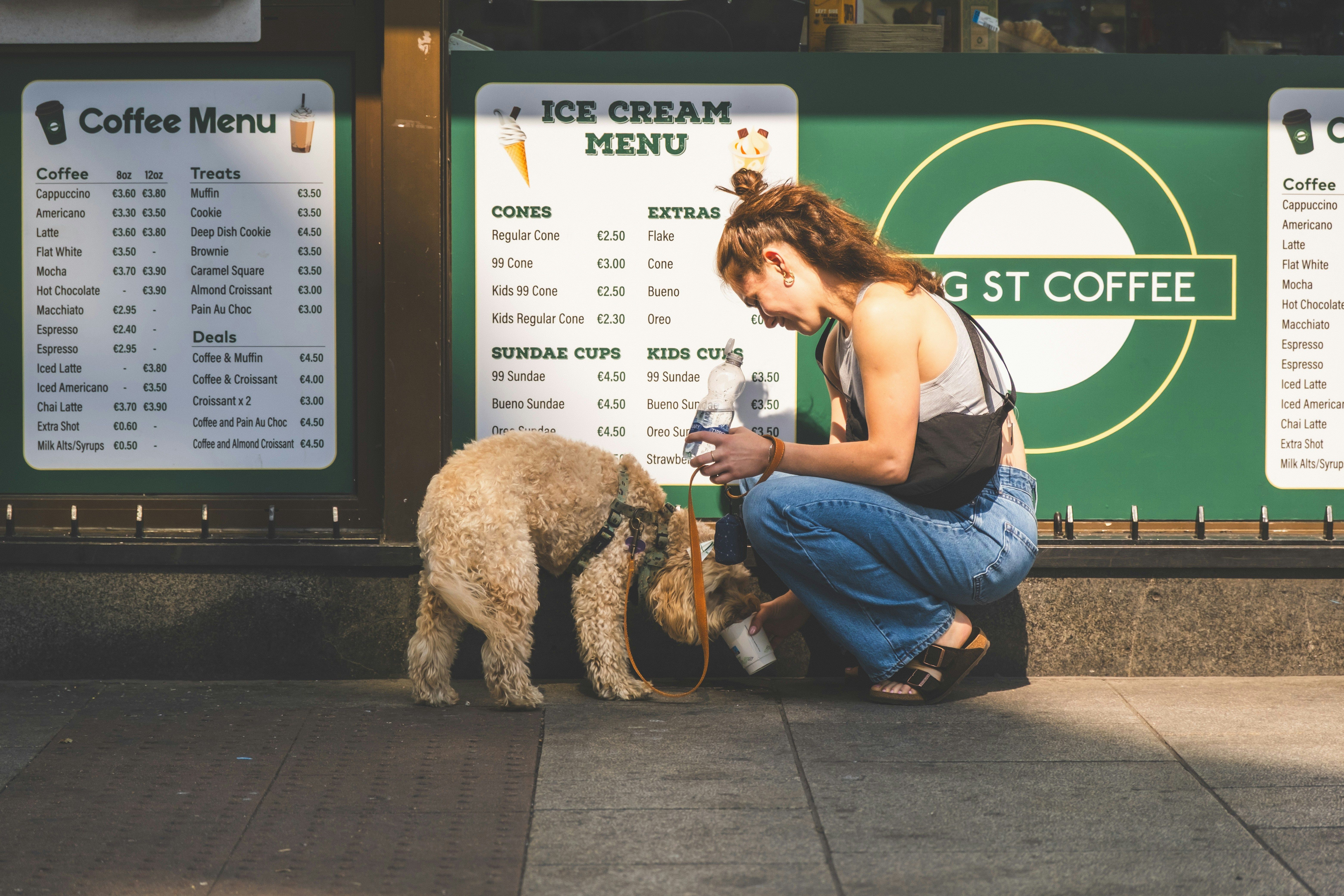 Woman feeding a small dog outside a coffee shop