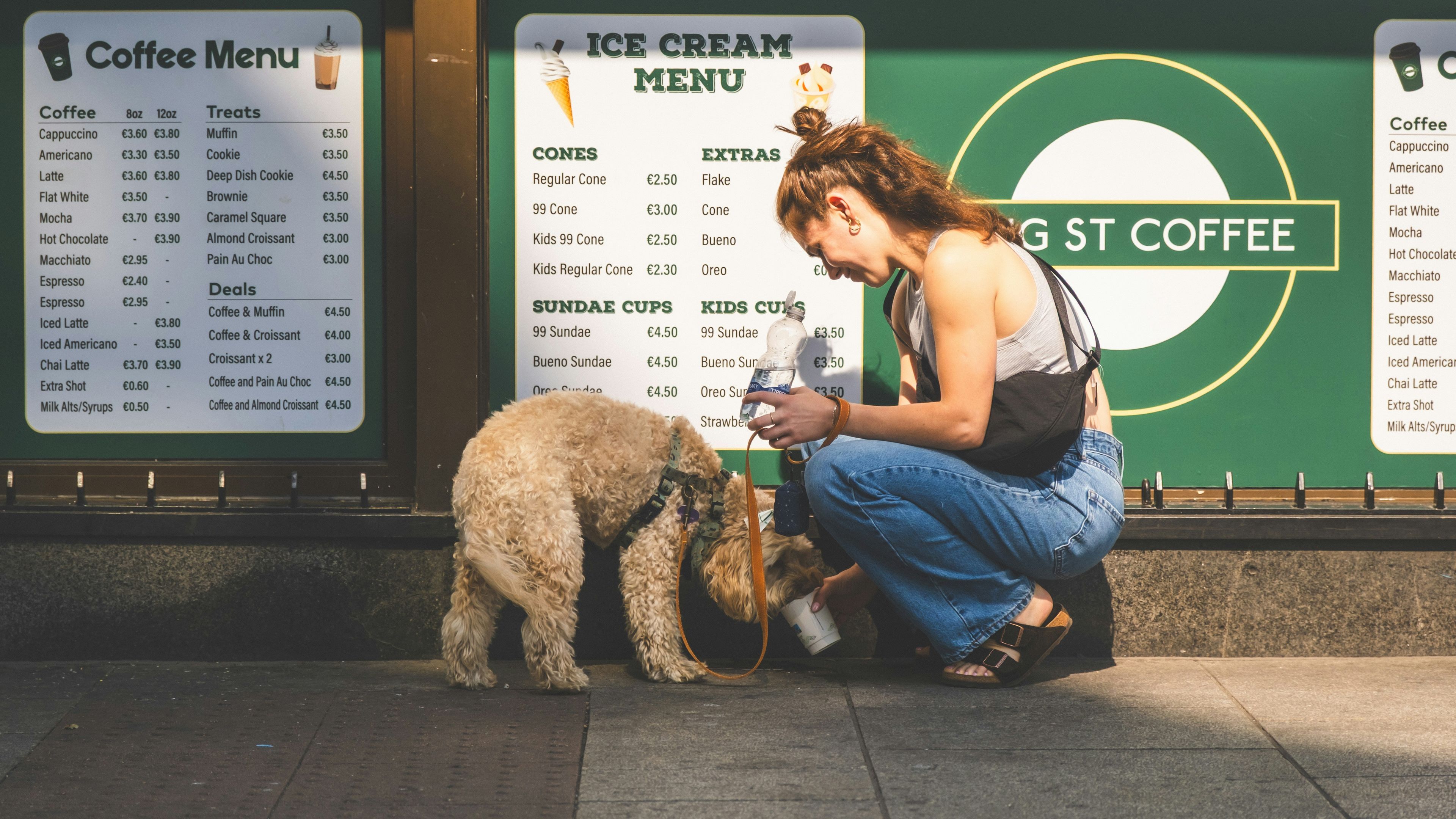 Woman feeding a small dog outside a coffee shop