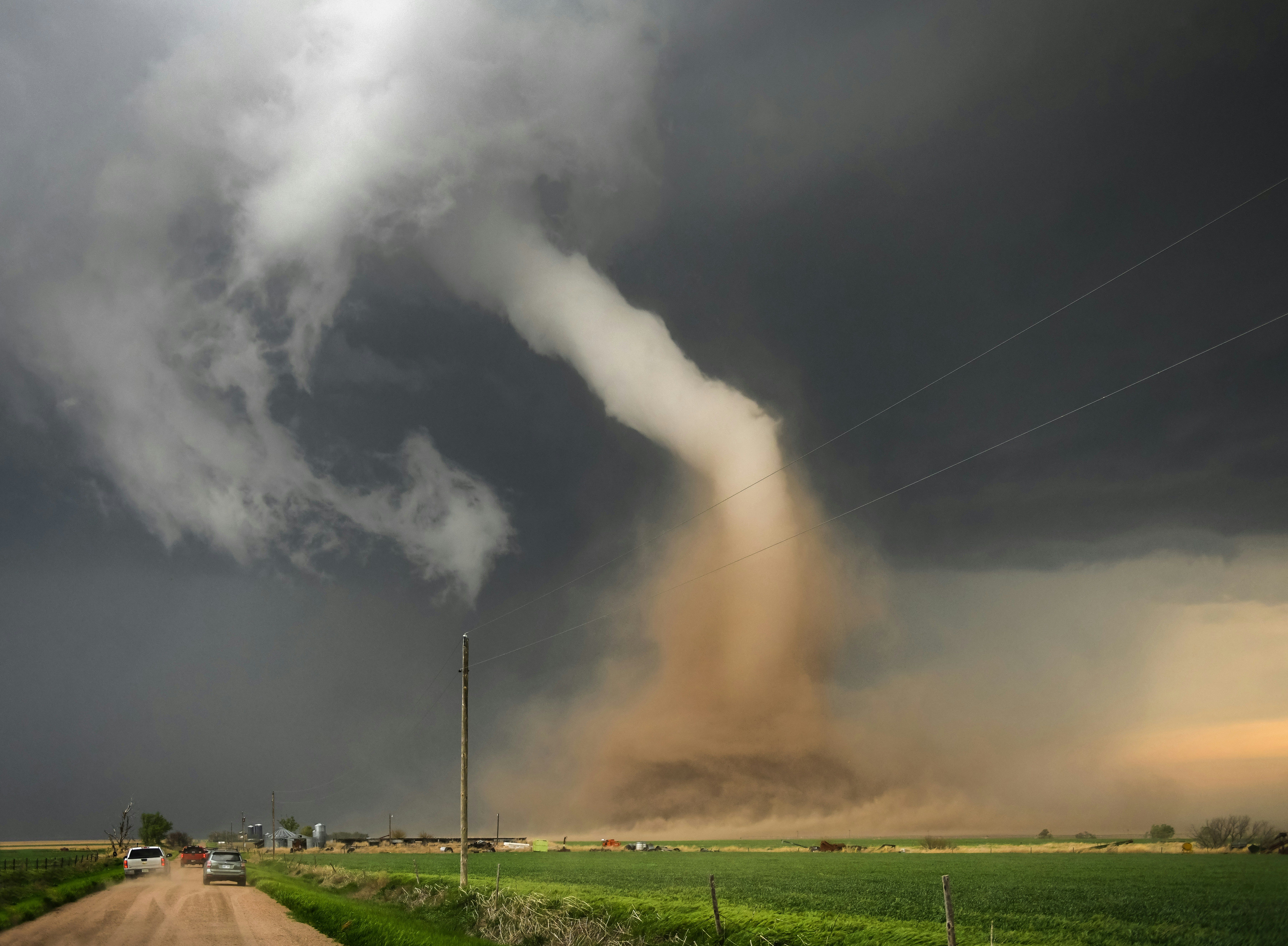 A large storm cloud is coming in over a dirt road