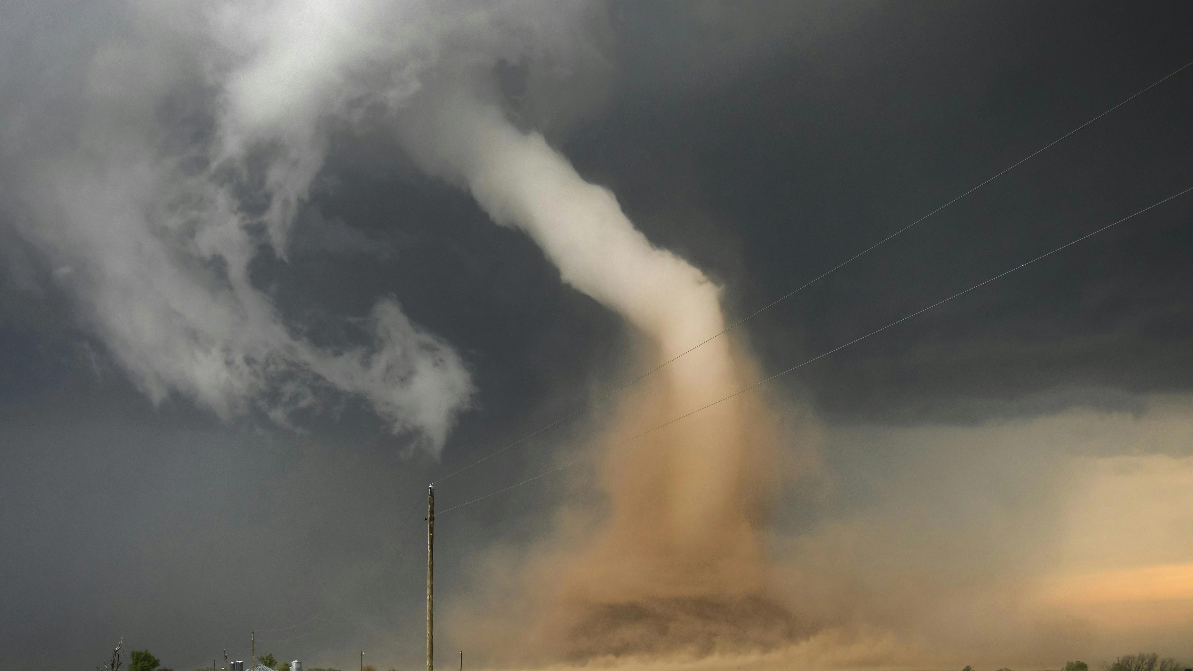 A large storm cloud is coming in over a dirt road