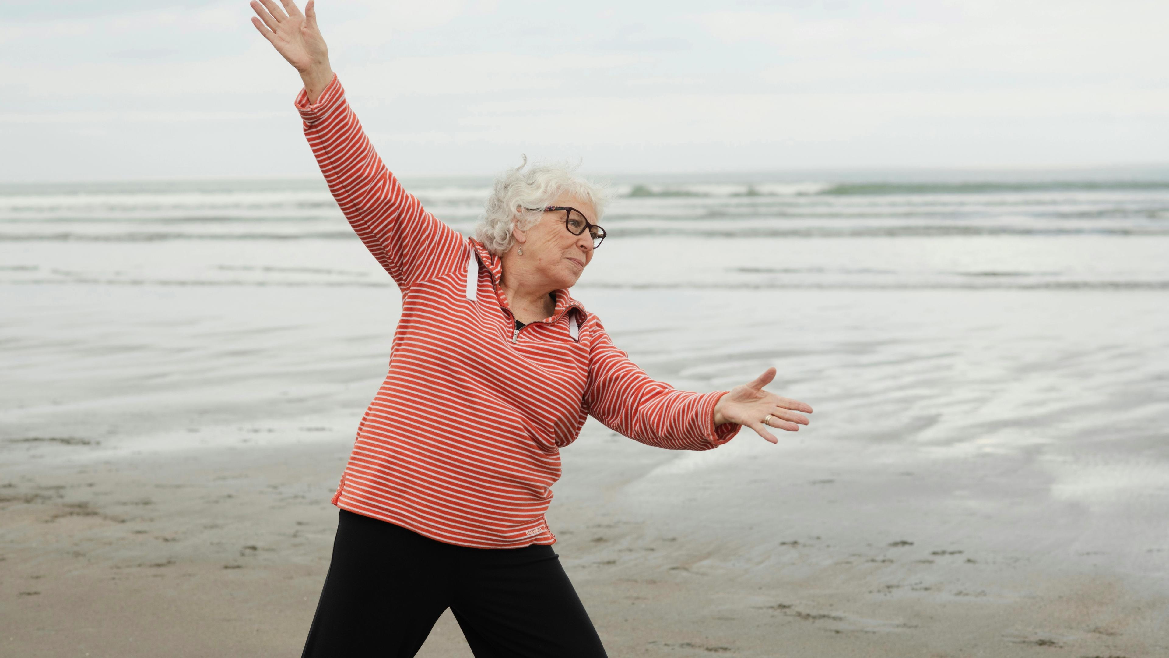 Woman exercises at the beach with outstretched arms