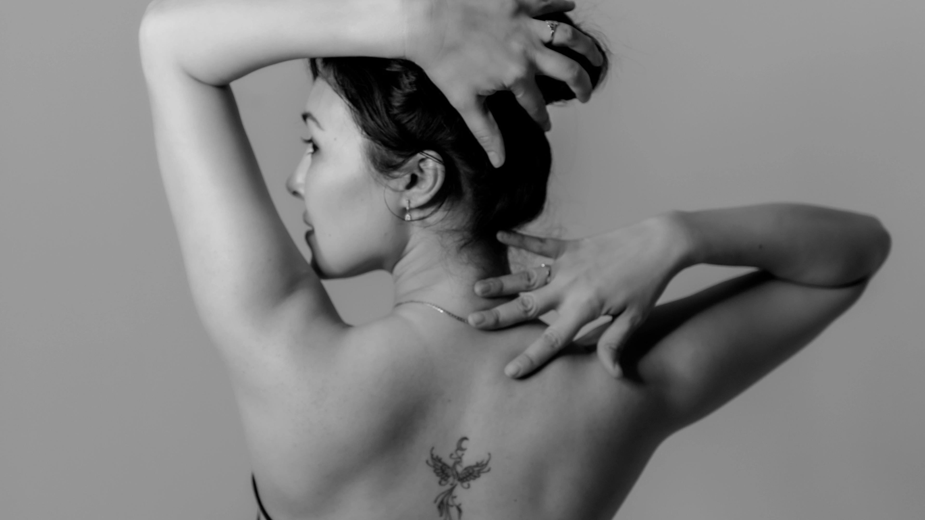 A black and white photo of a woman with tattoos on her back