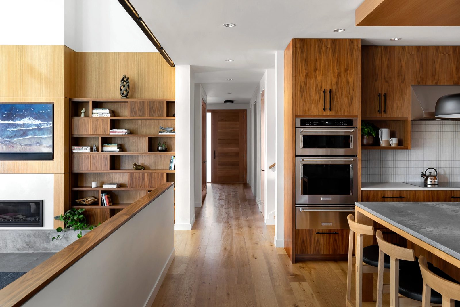 View past the fireplace and bookcase down a long hall to the kitchen and a fir front door