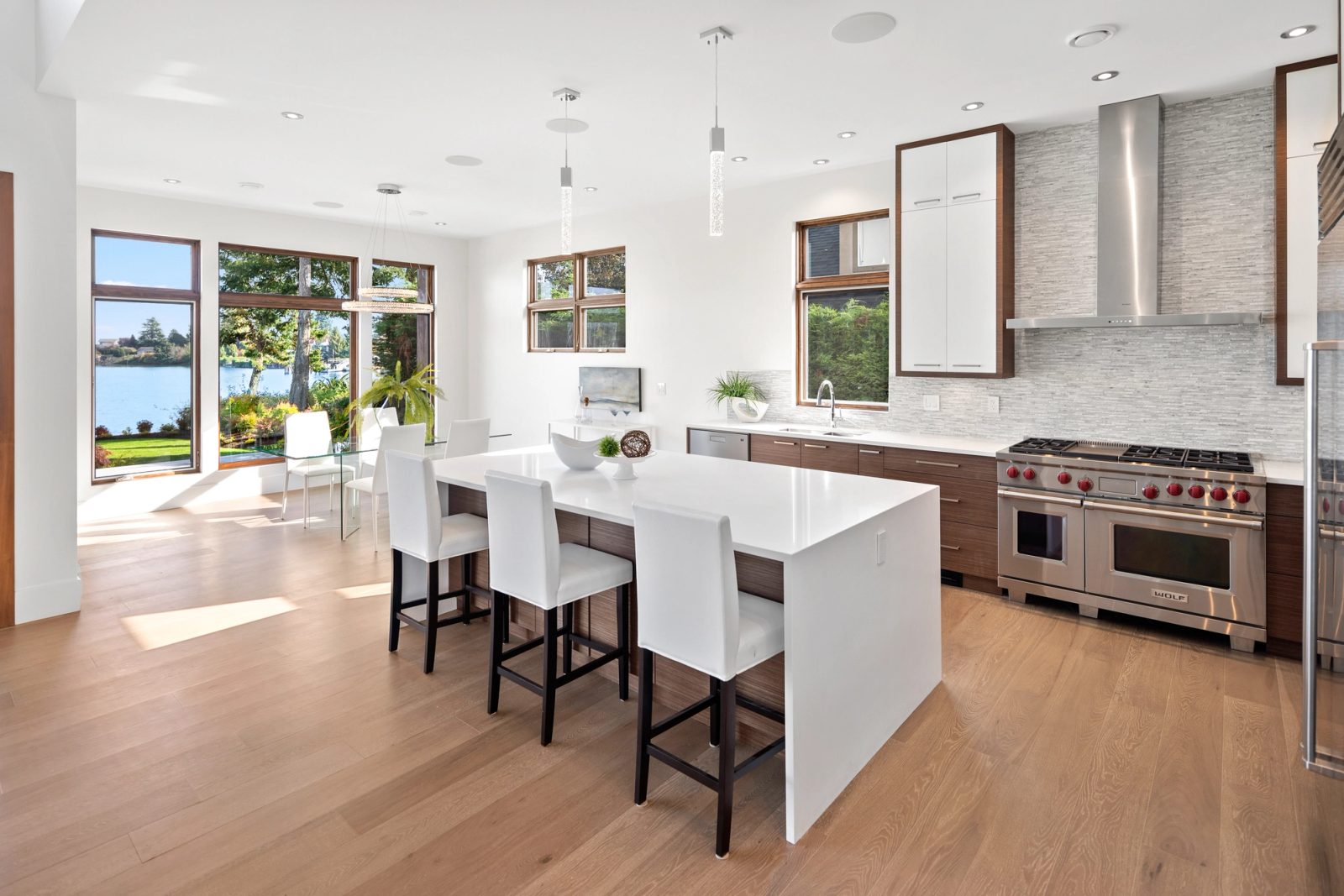 Open kitchen with a quartz island seating four, walnut cabinetry and a dining area facing the water