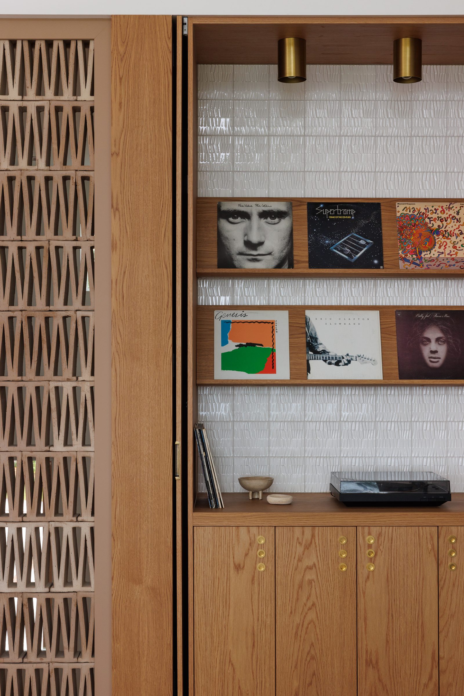 Right: records shelved in oak against white textured tile, a turntable below, the block screen at the frame's edge.