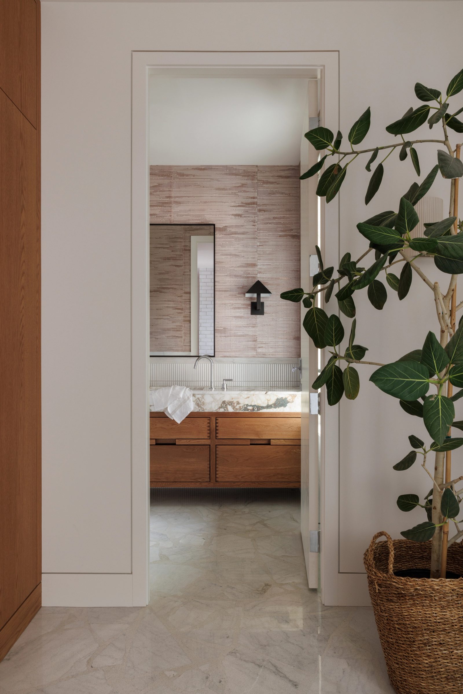 Left: a powder room seen through an open door from the hall, its marble vanity and black-framed mirror framed by the opening.