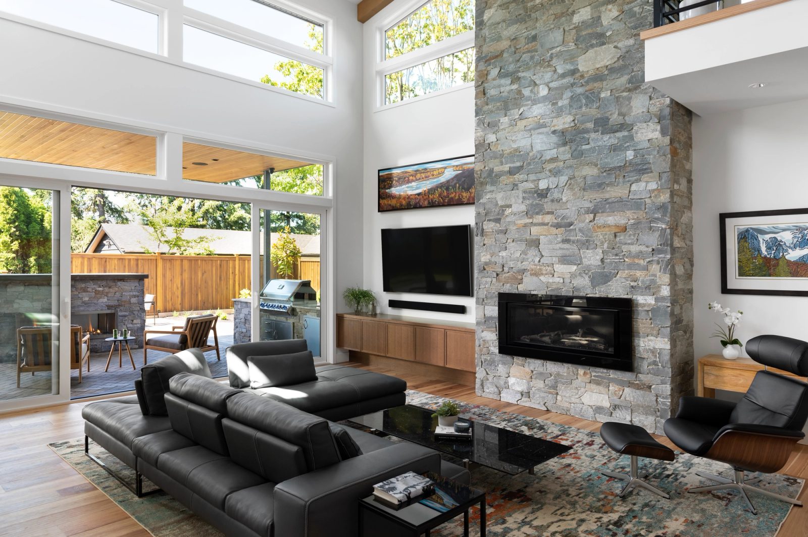 Living room with a linear gas fireplace in stacked stone and sliding doors open to a covered patio
