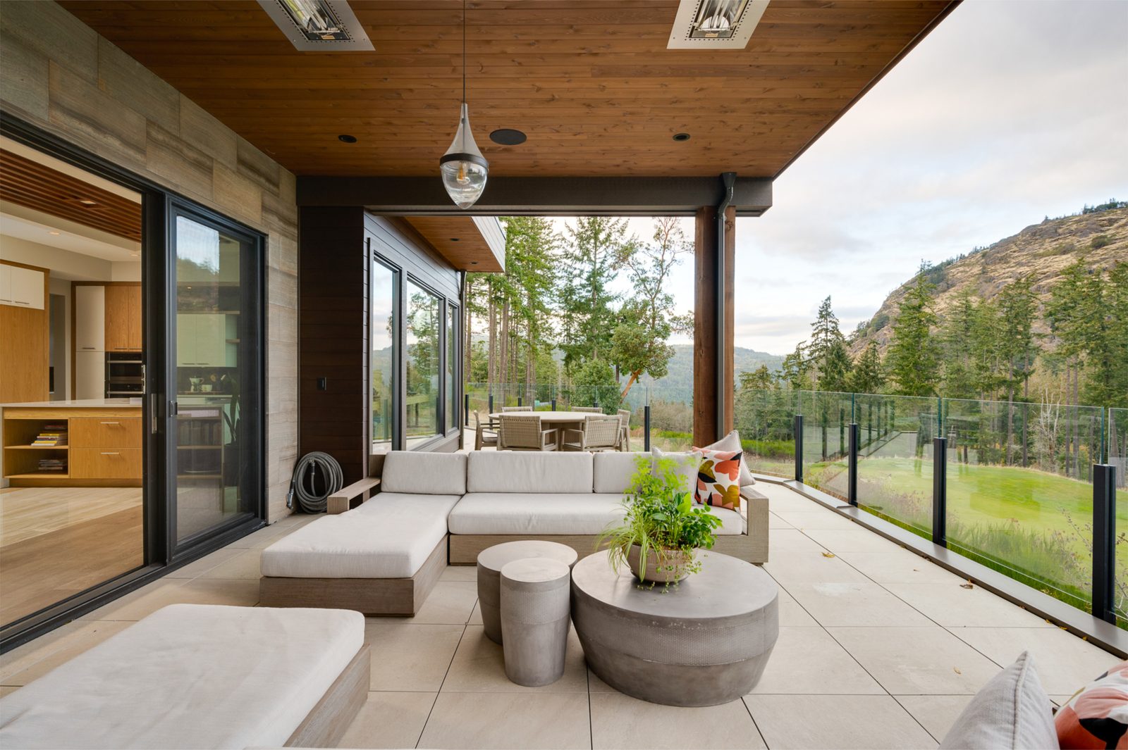 Terrace seating under infrared heaters, with the kitchen visible through open sliding doors