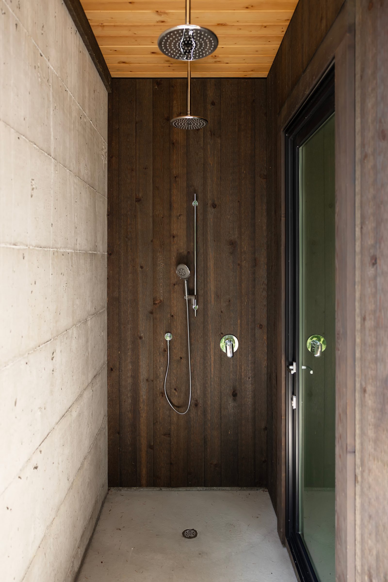 Outdoor shower between board-formed concrete and dark stained cedar