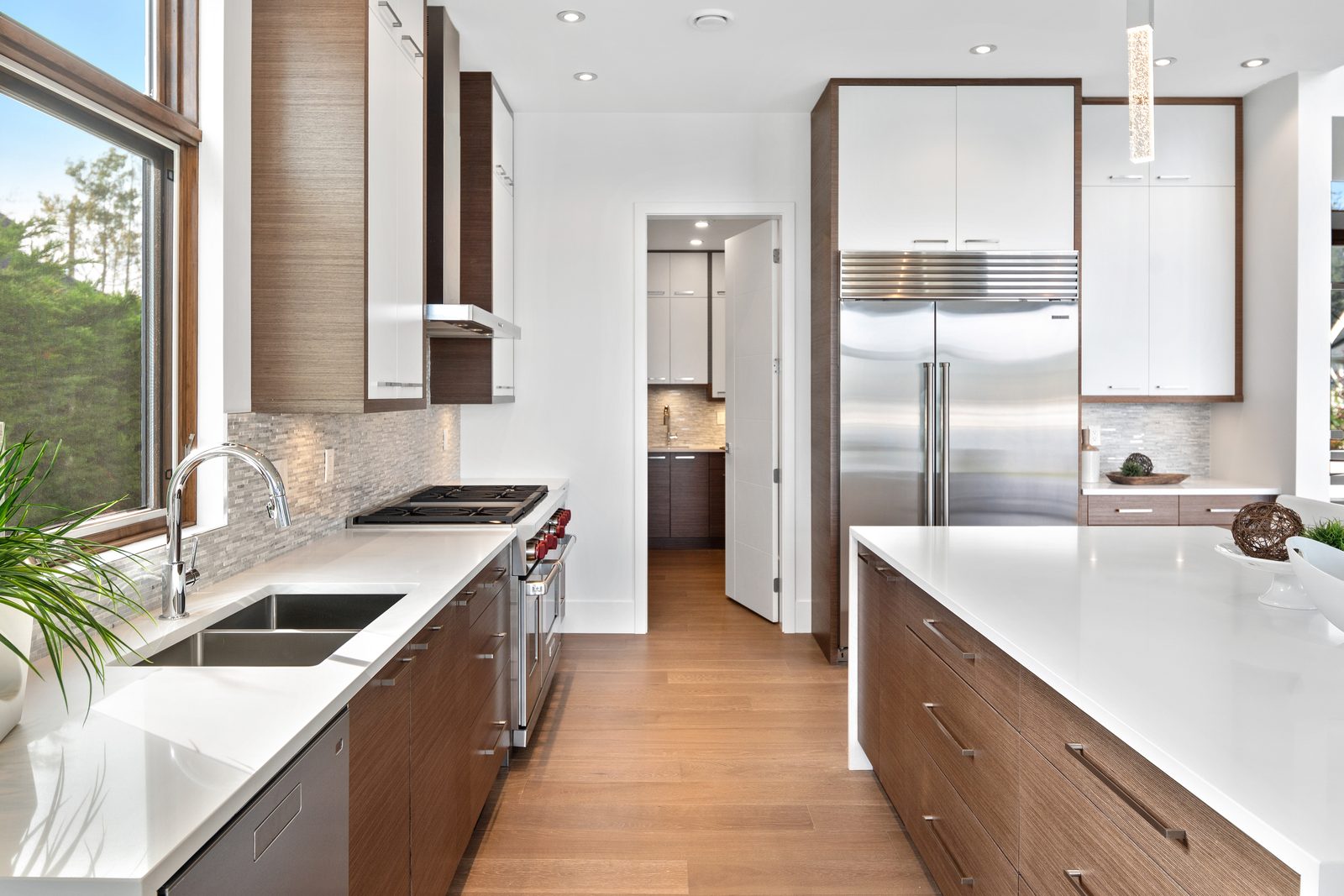 Kitchen sink and cooktop run in walnut and quartz, with a walk-in pantry beyond