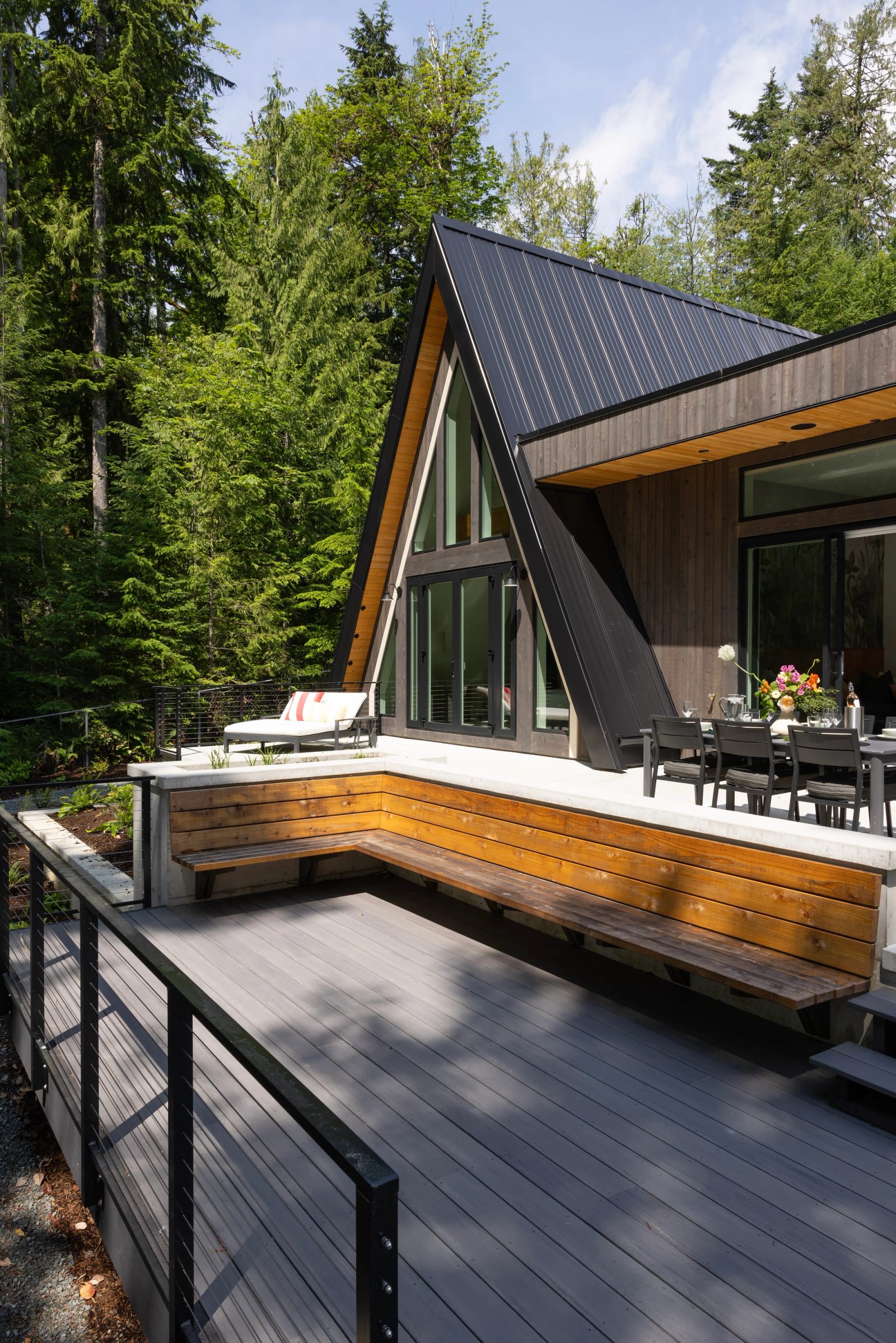 Cedar bench wrapping a concrete deck below a black A-frame gable