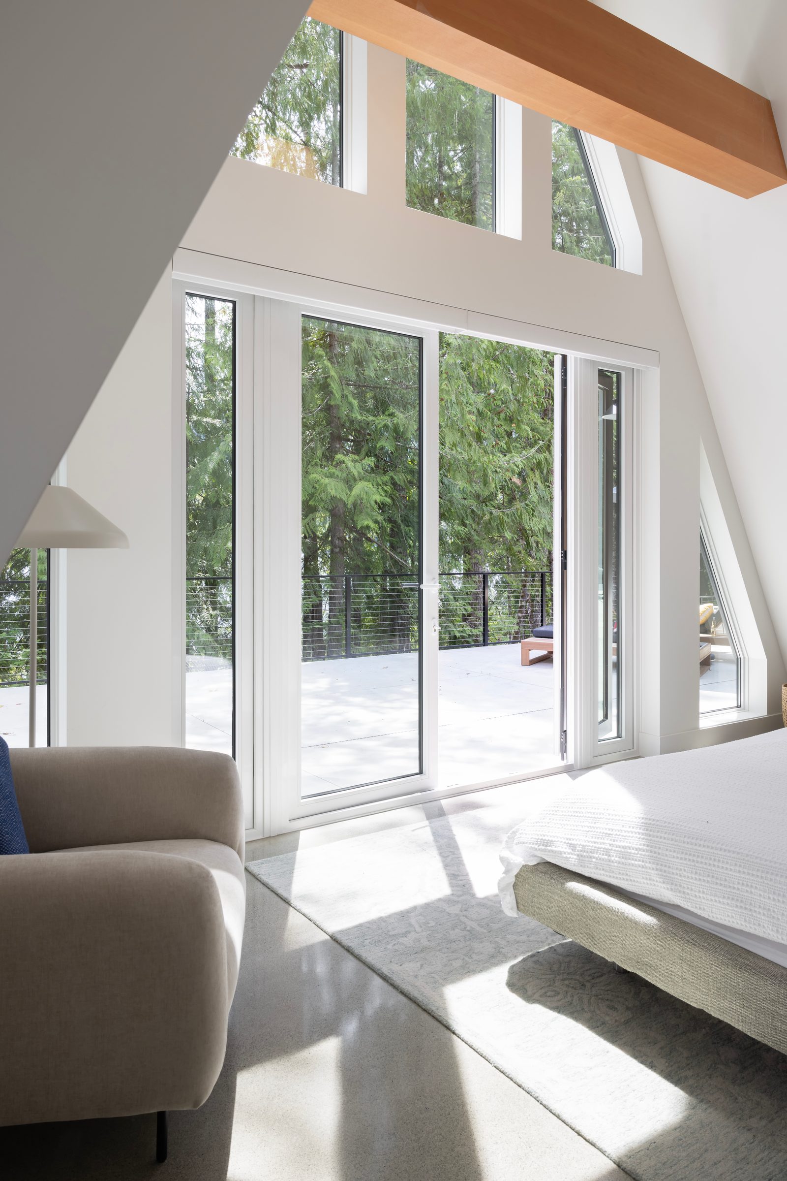 Bedroom doors opening onto a concrete terrace among firs