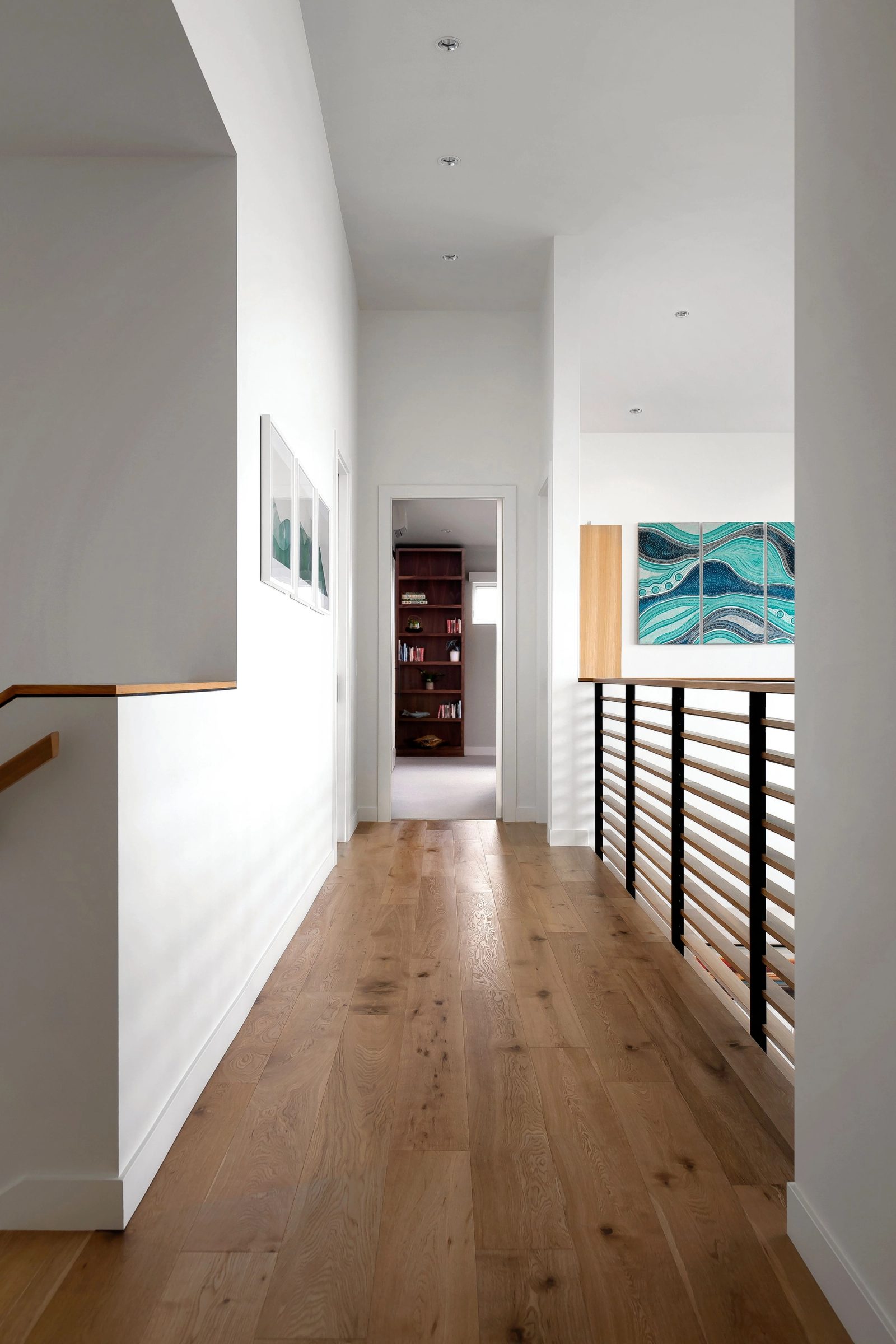 Upper hall in white oak with a horizontal slat rail and a triptych on the wall