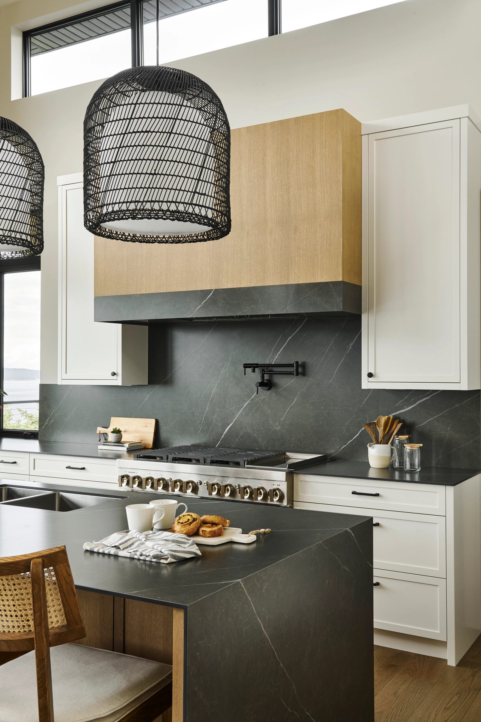 Oak hood above a soapstone backsplash and range, woven pendants over the island