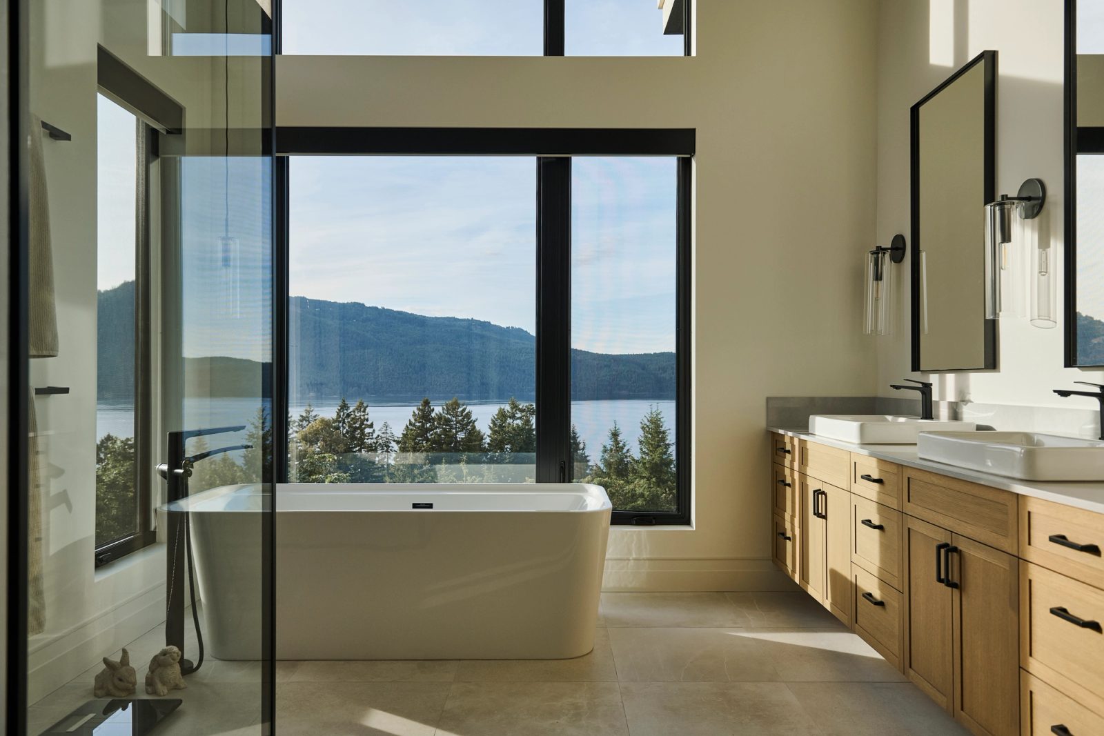 Freestanding tub against full-height glazing, twin oak vanity, Mt Tuam across the water