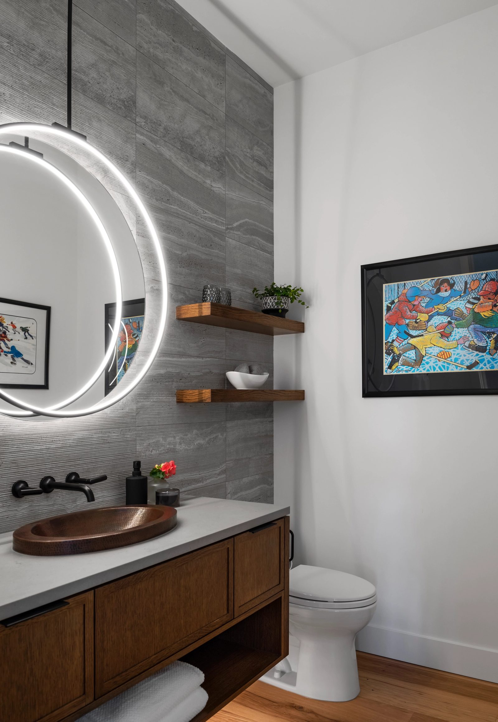 Powder room with a hammered copper basin, a ring-lit round mirror and a travertine-look tile wall