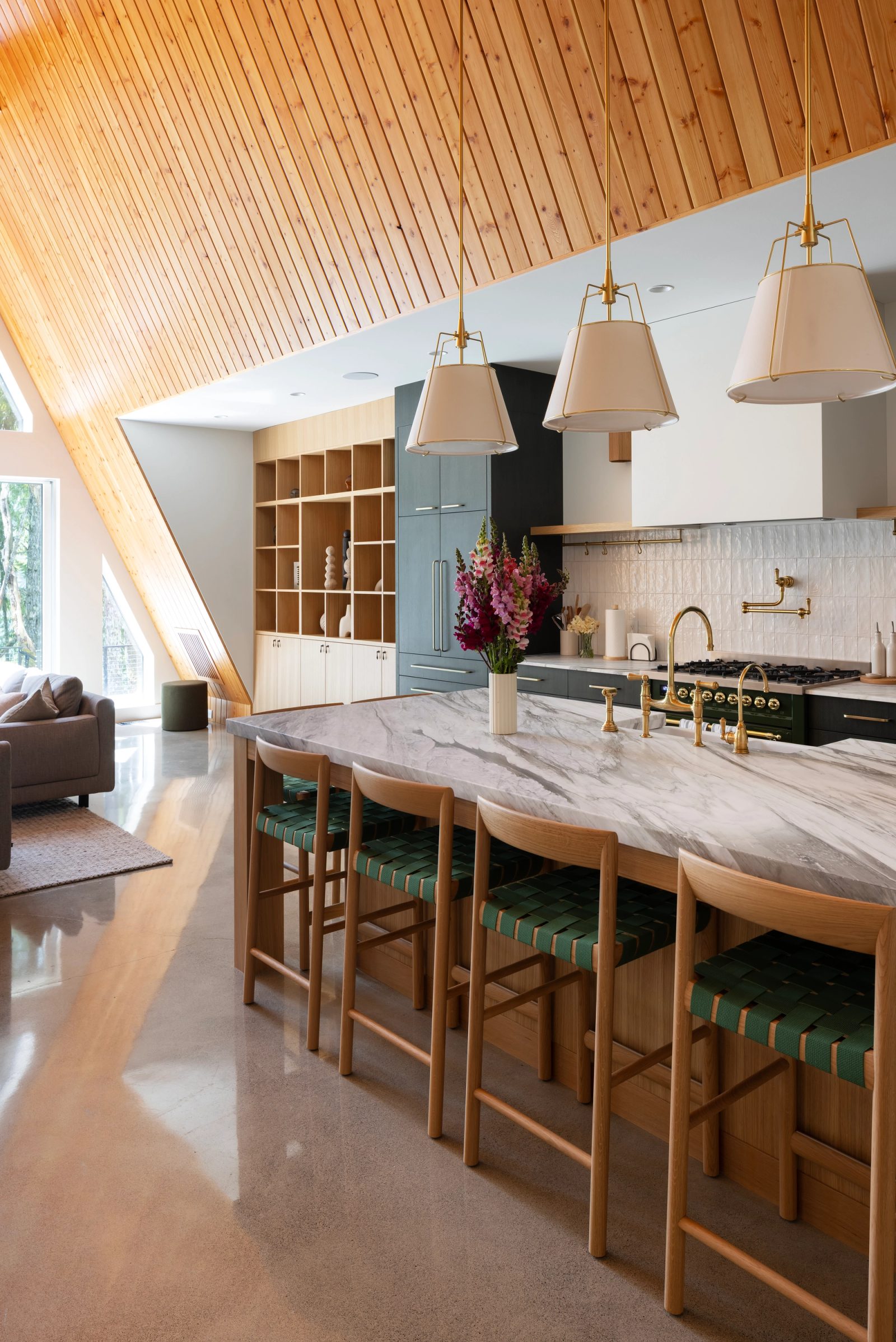 Marble-topped island with brass fittings below a pale cedar ceiling