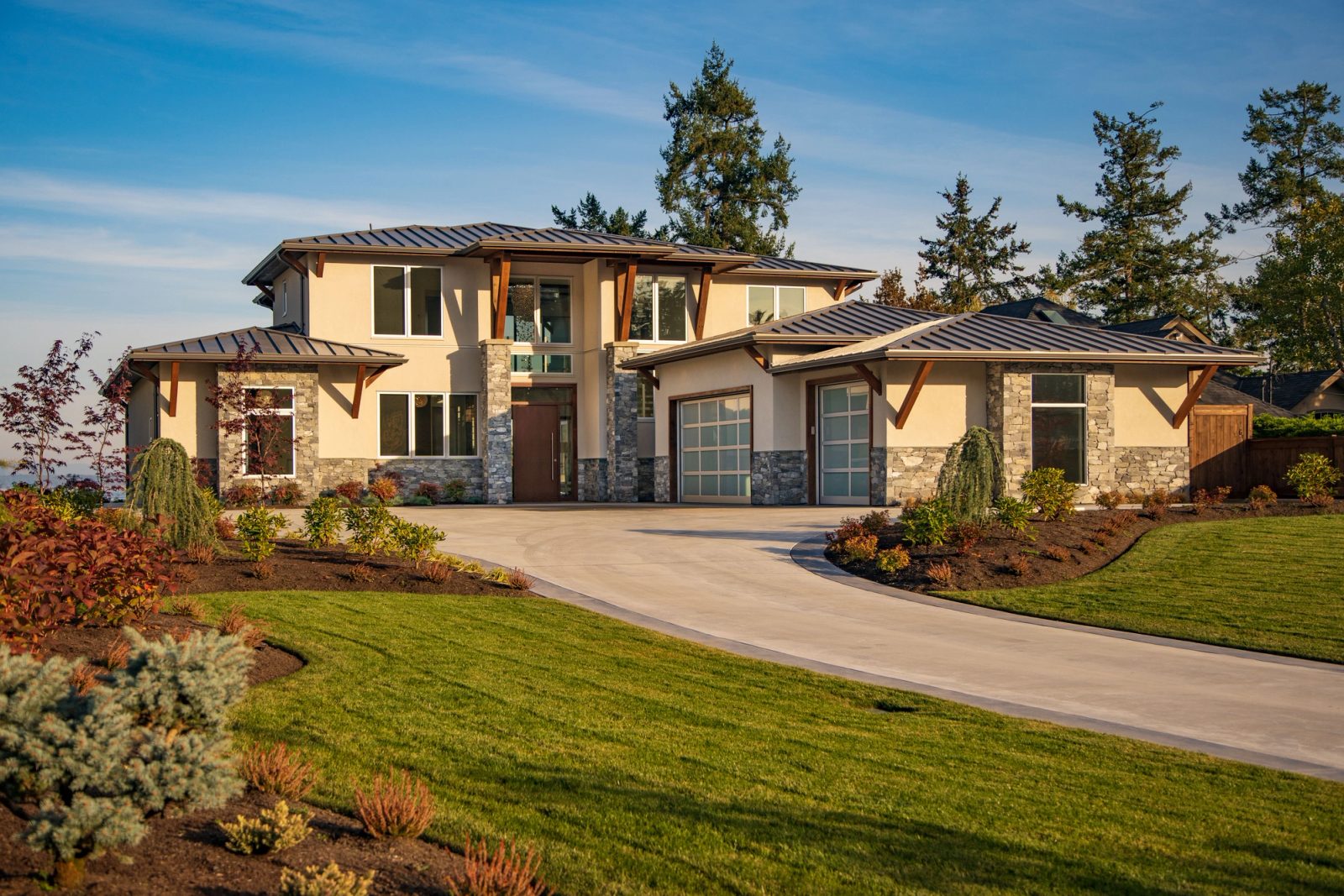 Contemporary house at golden hour with a hipped metal roof, timber brackets and a curved concrete driveway