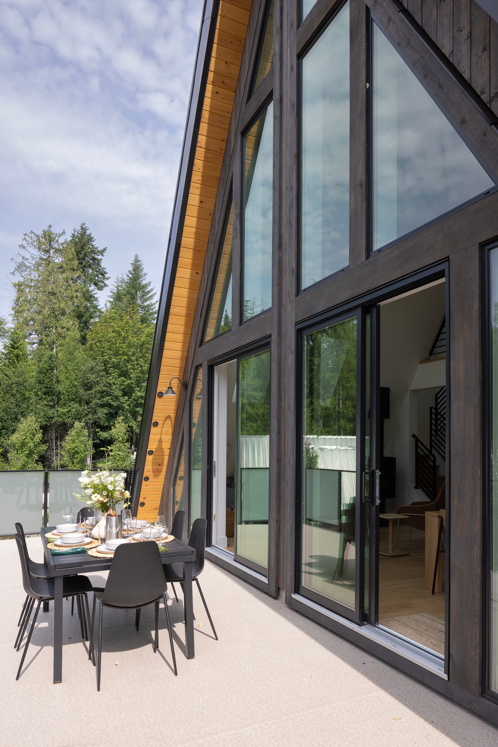 Dining table on a concrete terrace beside full-height glazing