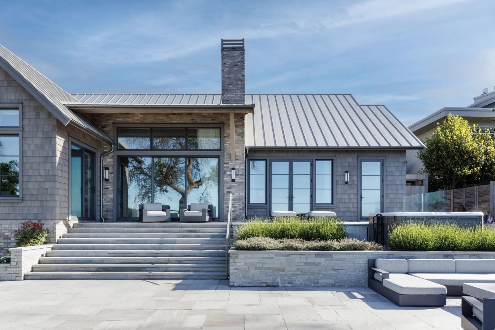 The water-side elevation with its brick chimney, standing-seam roof and covered terrace