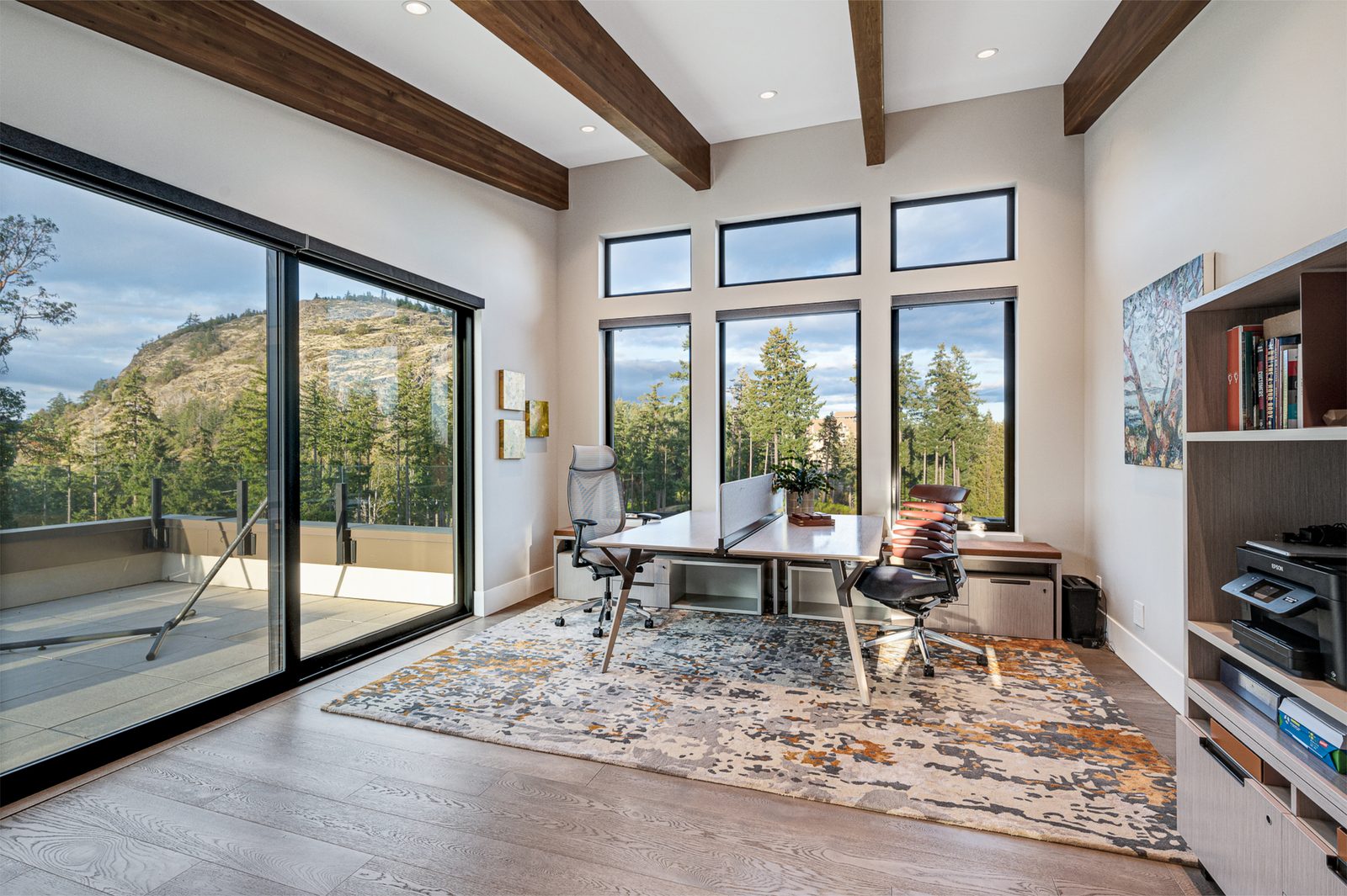 Home office with a shared desk facing full-height windows and a sliding door to a terrace