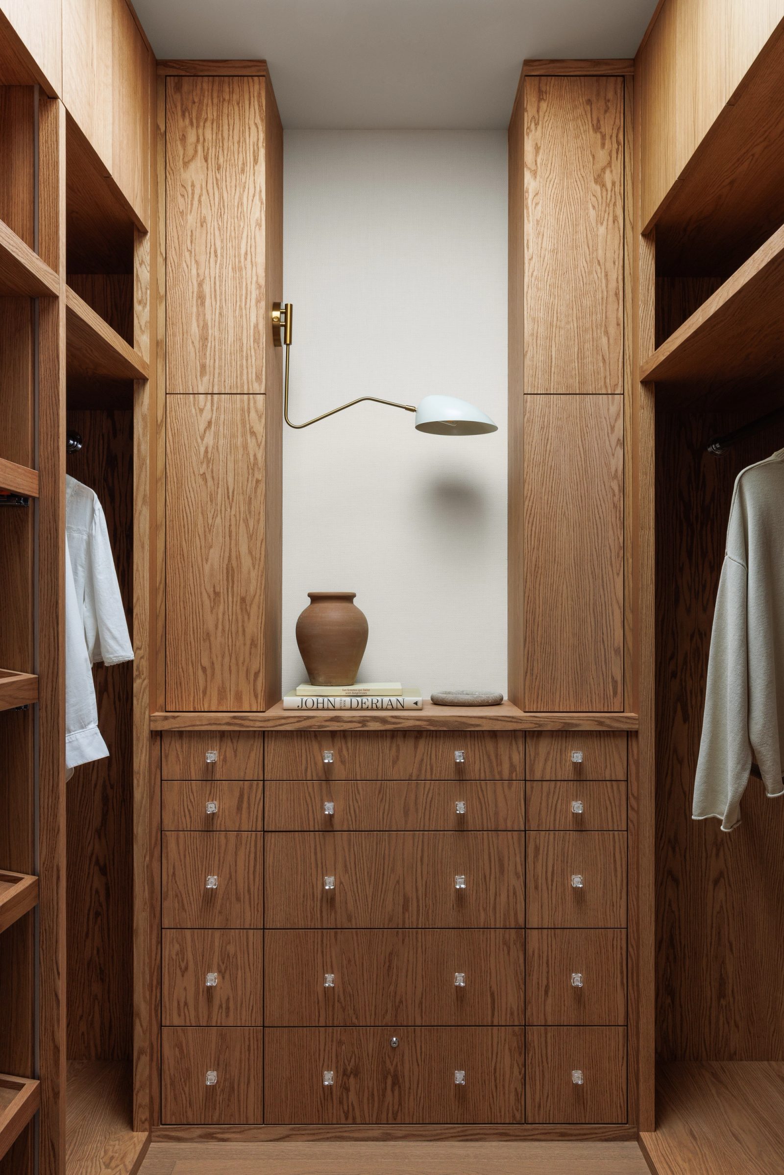 Left: a dressing room lined floor to ceiling in oak, a brass swing-arm lamp over a terracotta jar on the counter.