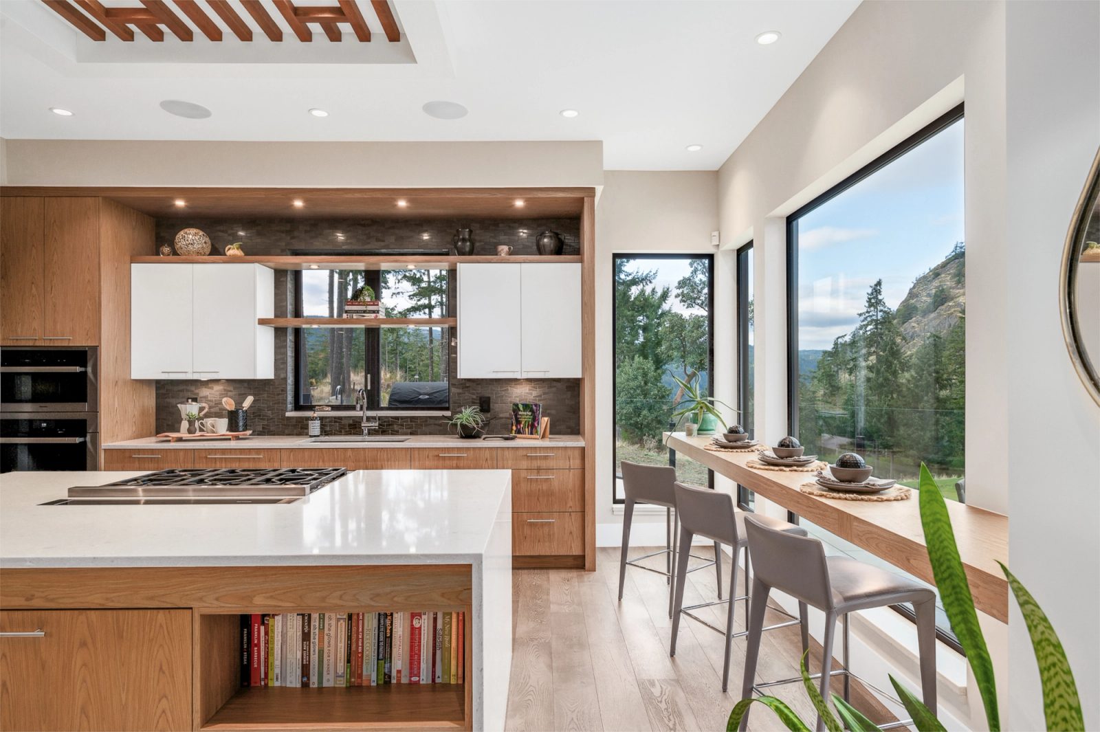 Kitchen island with a gas cooktop, looking past to an oak counter set along the window