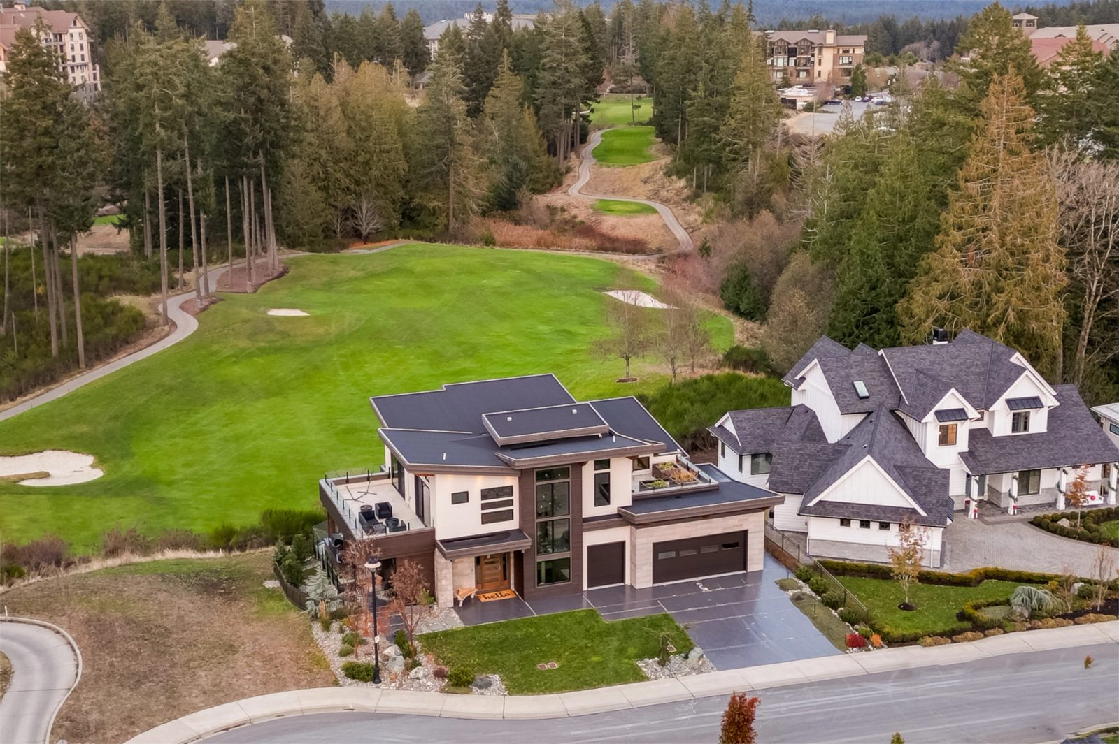 Aerial from the southwest. The site frame: fairway, roof deck, the drop to the lower floor, the whole massing at once.