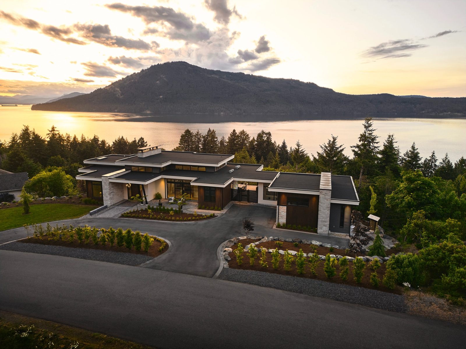 House from the air at sunset, flat roofs spreading above Satellite Channel and Mt Tuam