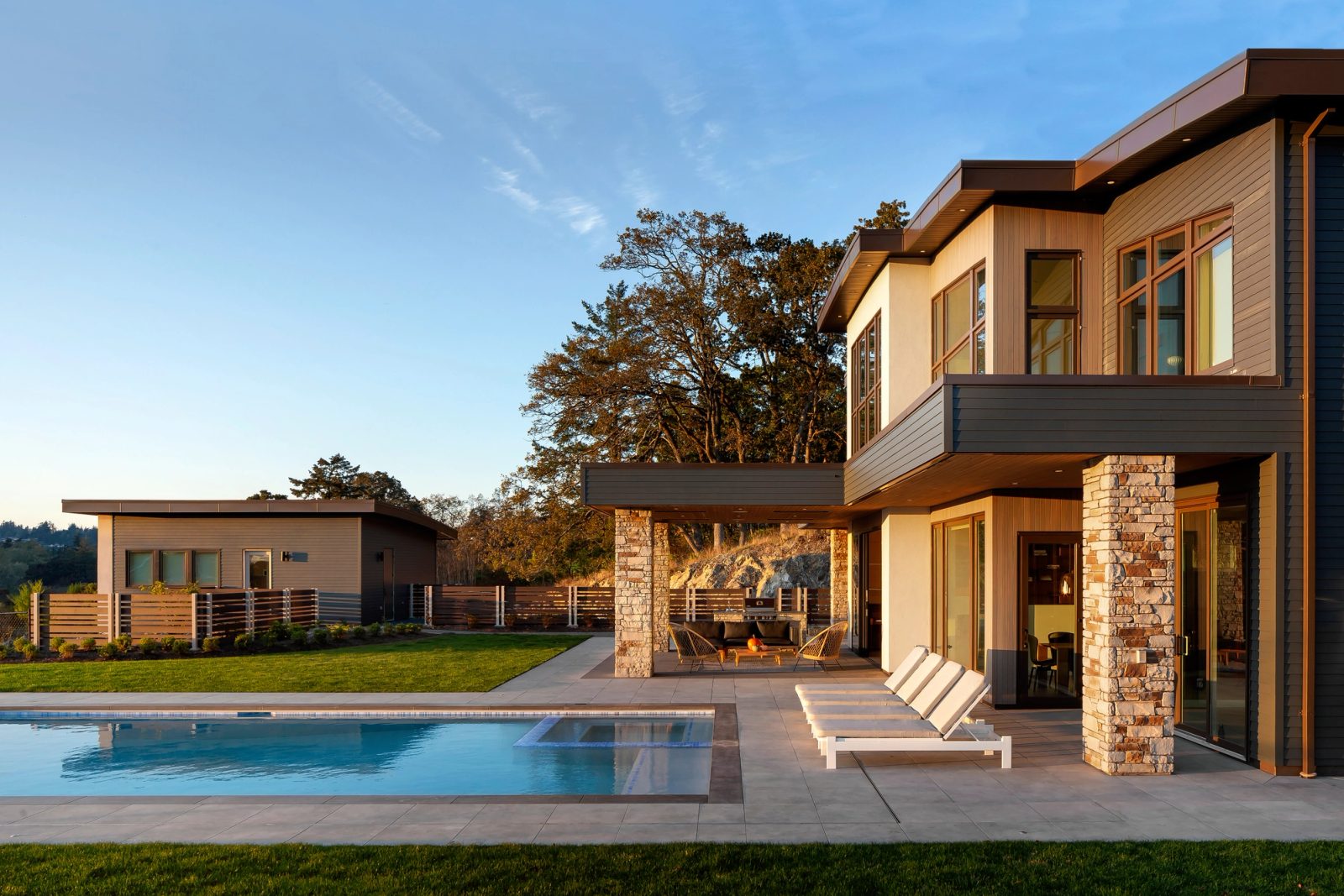 Pool and terrace at sunset with a single-storey guest house across the lawn