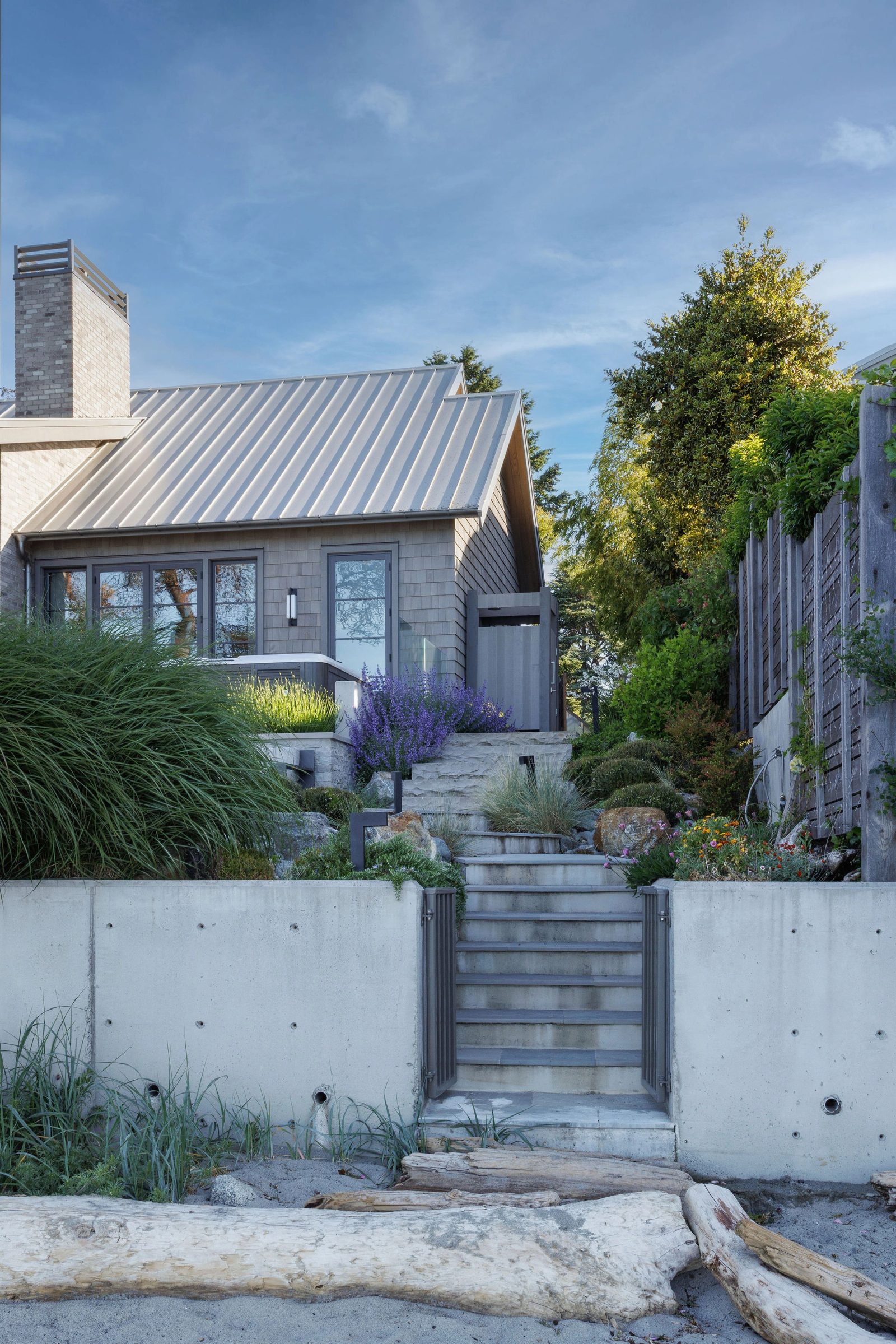 Stone steps rising from the sand through a gate in the seawall to the planted terrace above